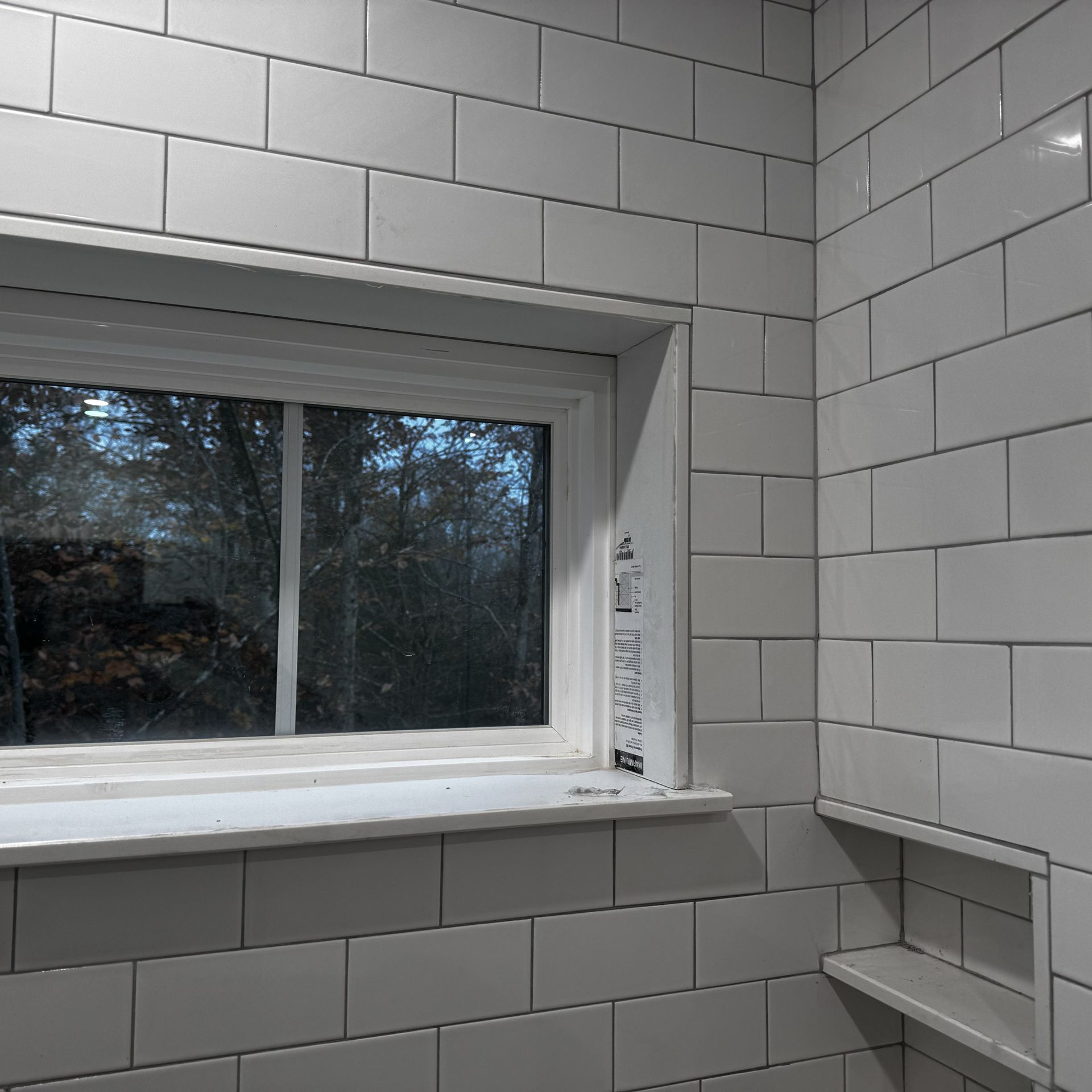 A bathroom with white tile walls and a window