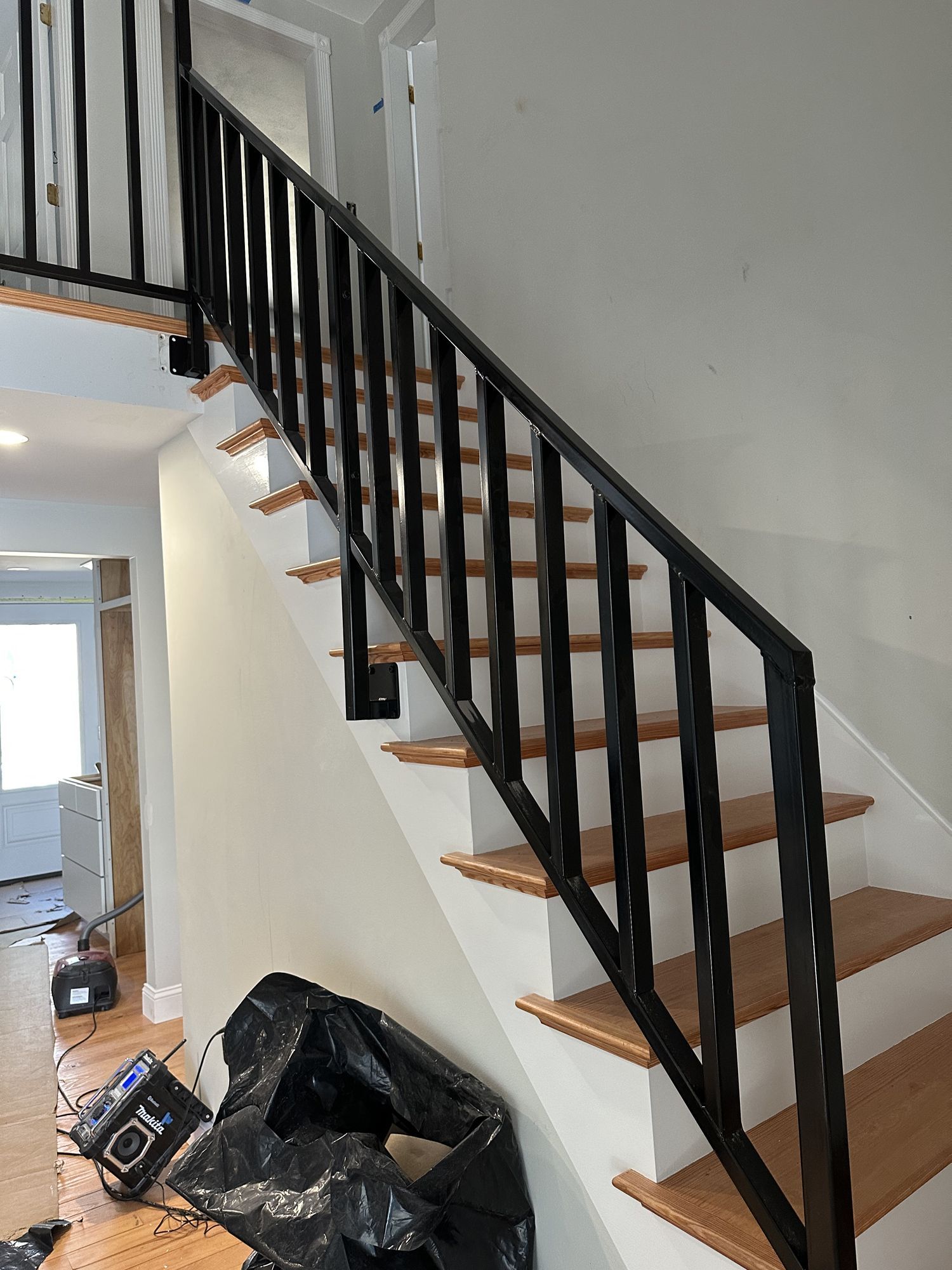 A staircase with a black railing and wooden steps in a house.