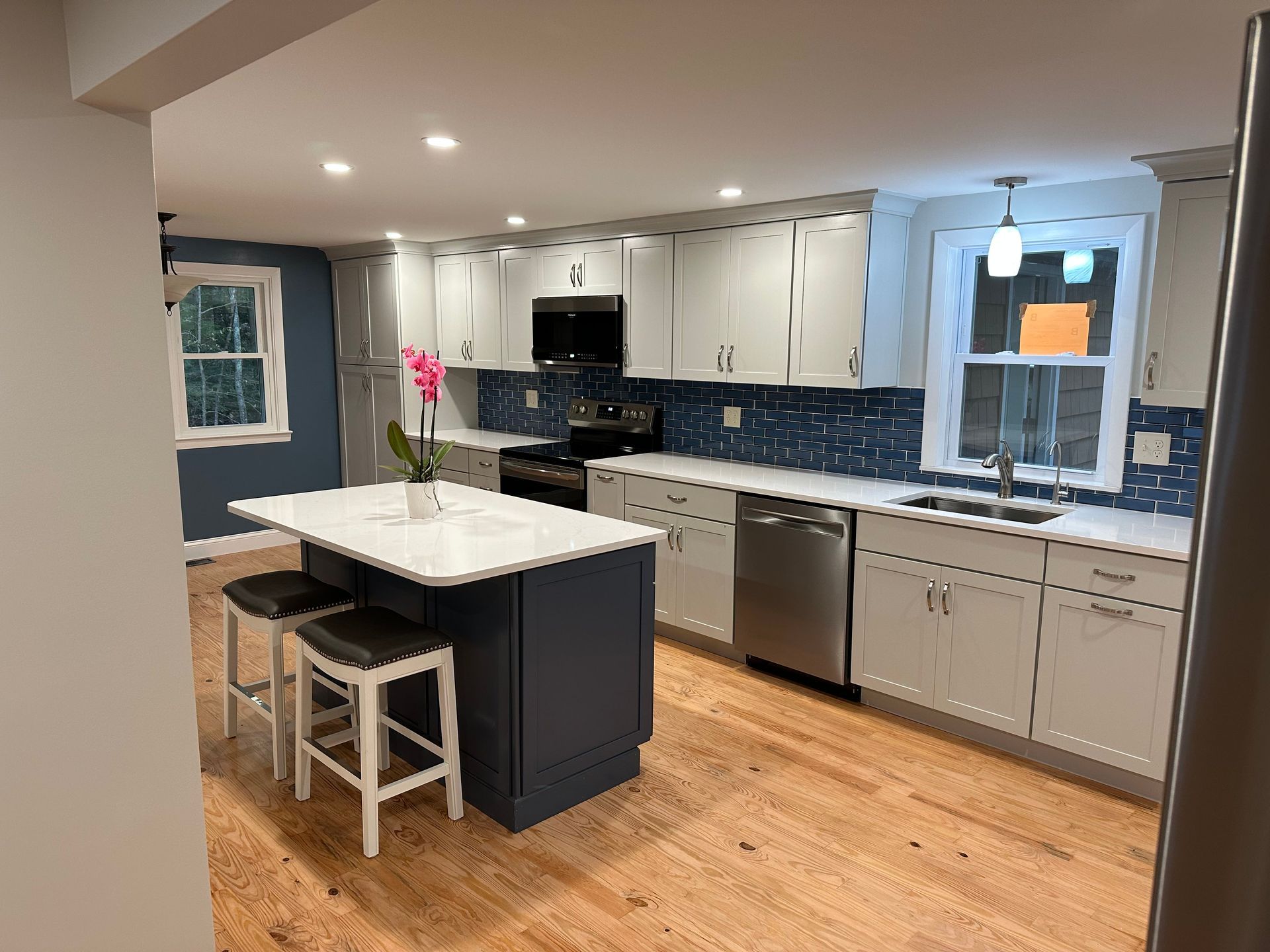 A kitchen with white cabinets , stainless steel appliances , and a large island.