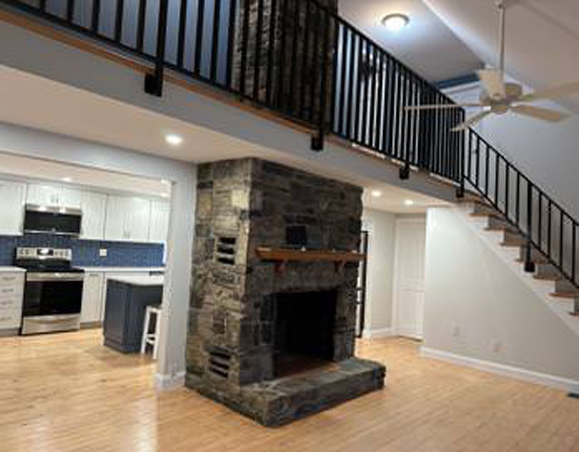 A living room with a fireplace and stairs in a house.