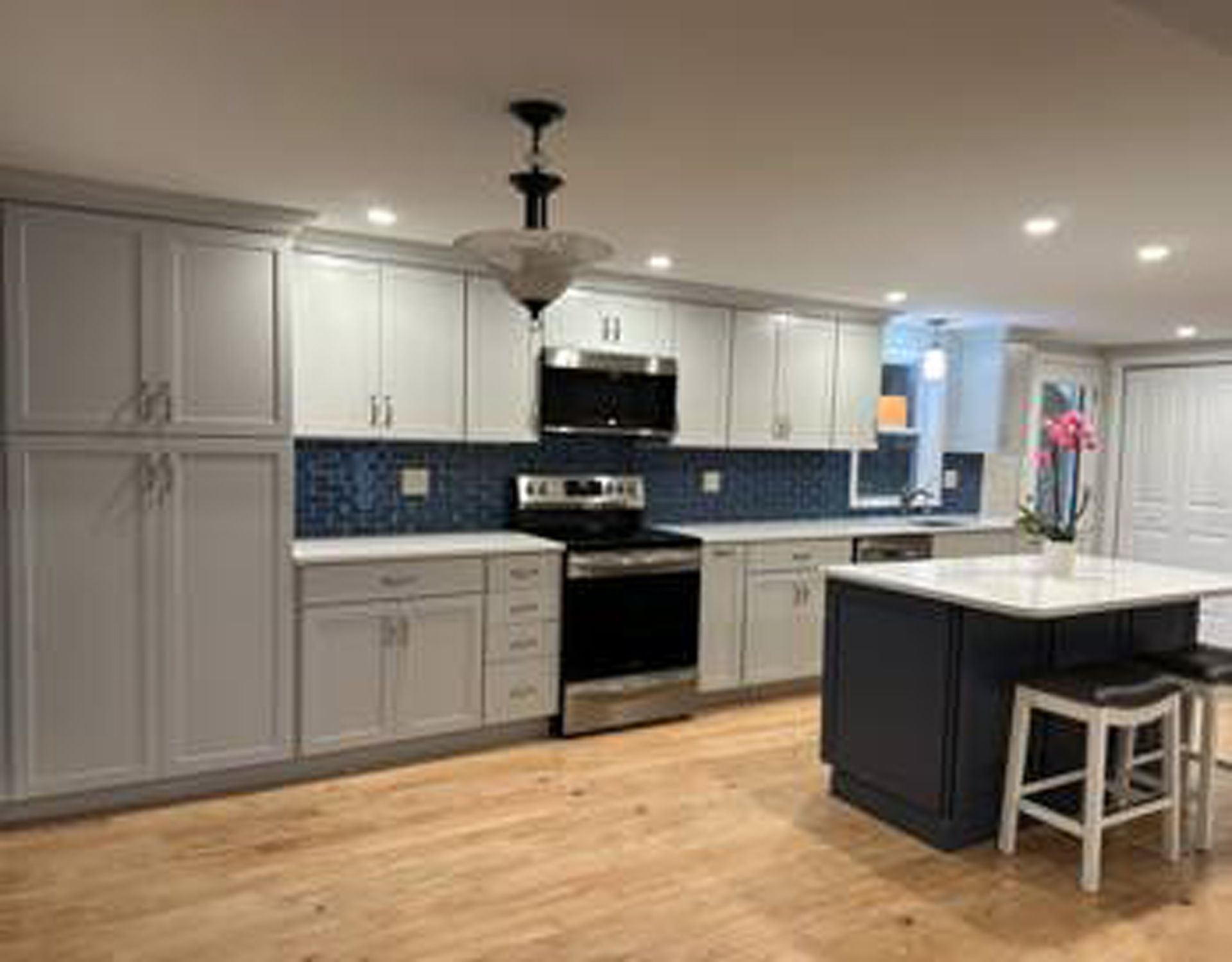 A kitchen with white cabinets , stainless steel appliances , and a large island.