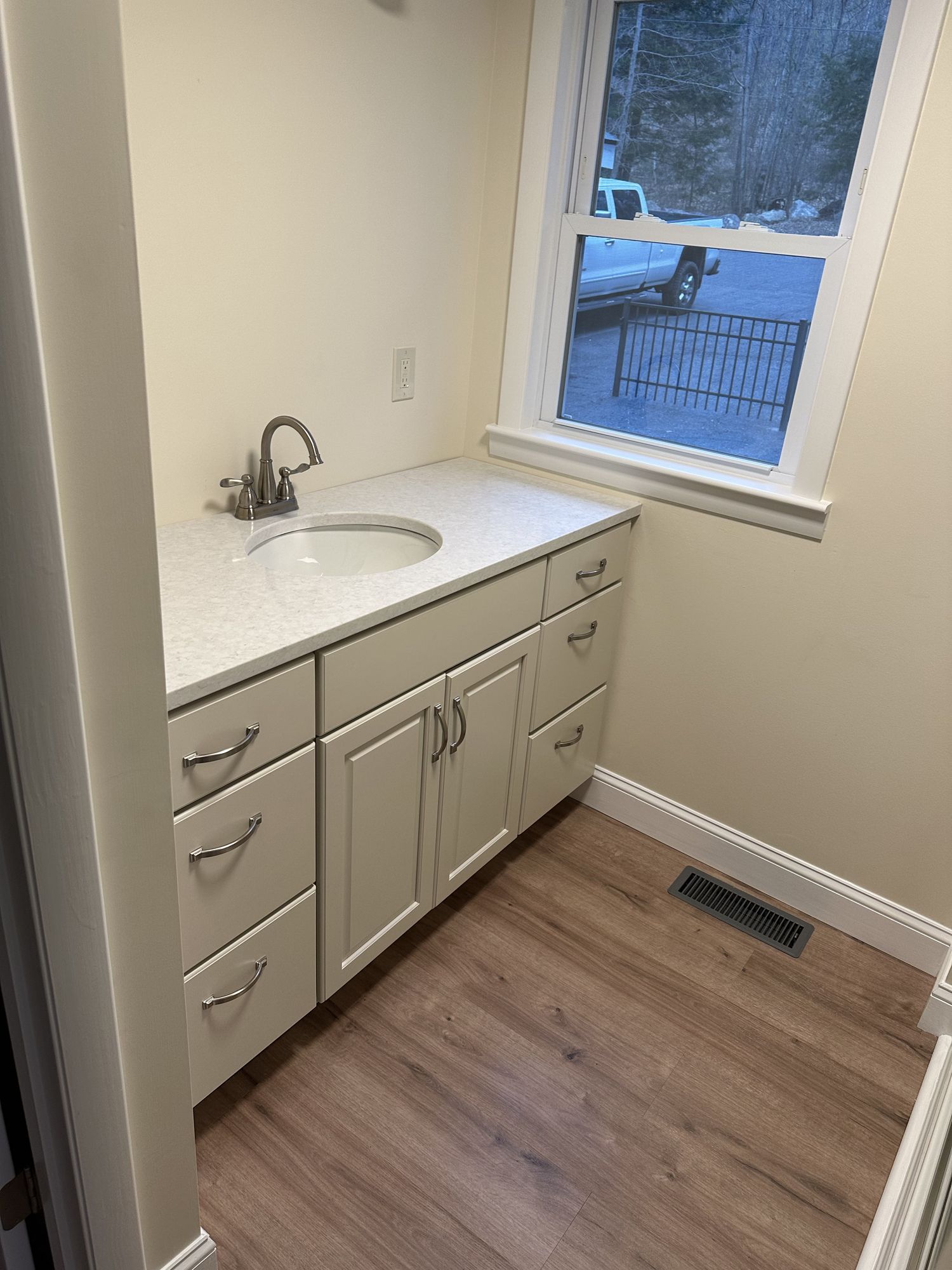 A bathroom with a sink , cabinets and a window.