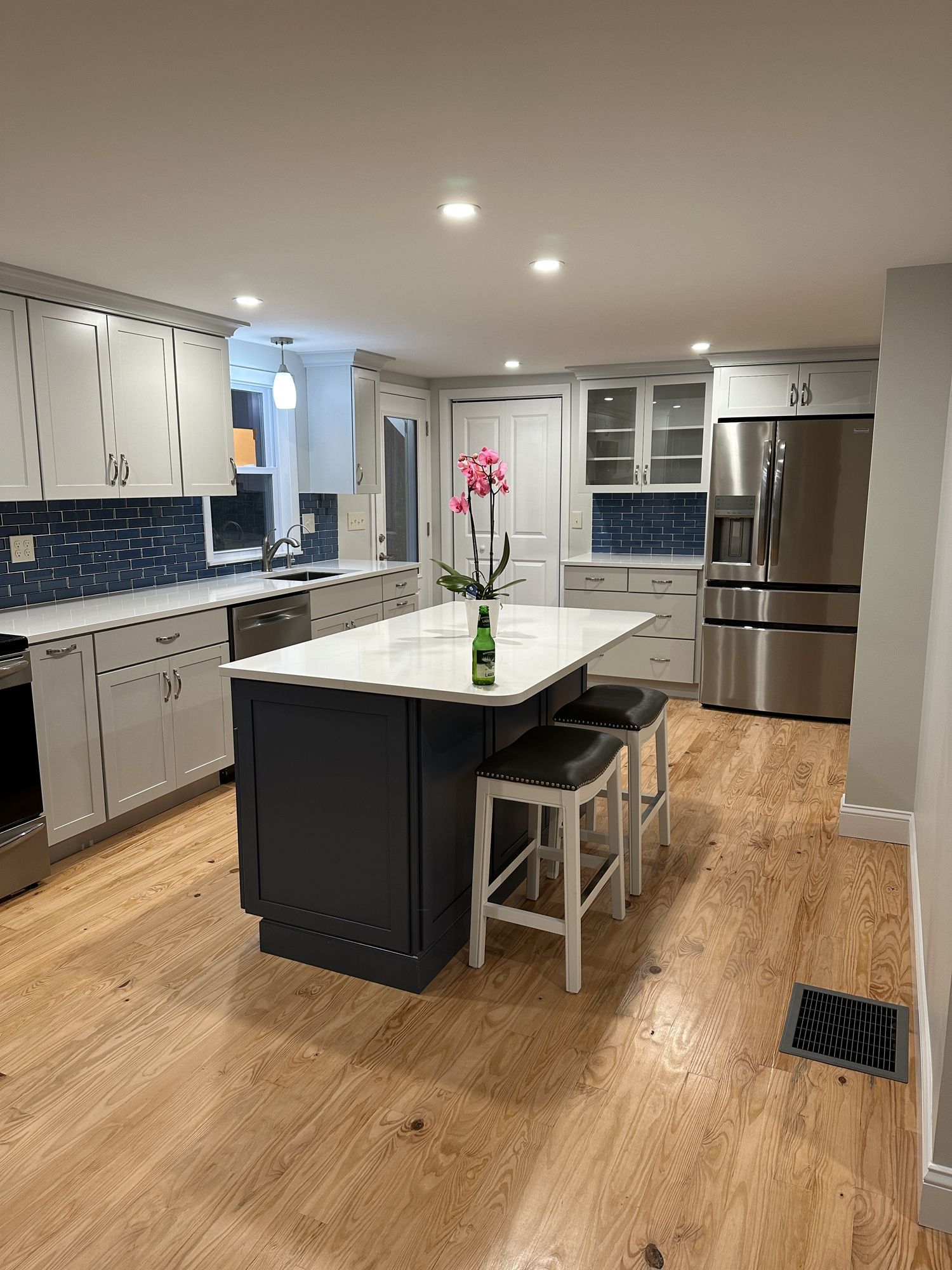 A kitchen with stainless steel appliances , hardwood floors , and a large island.