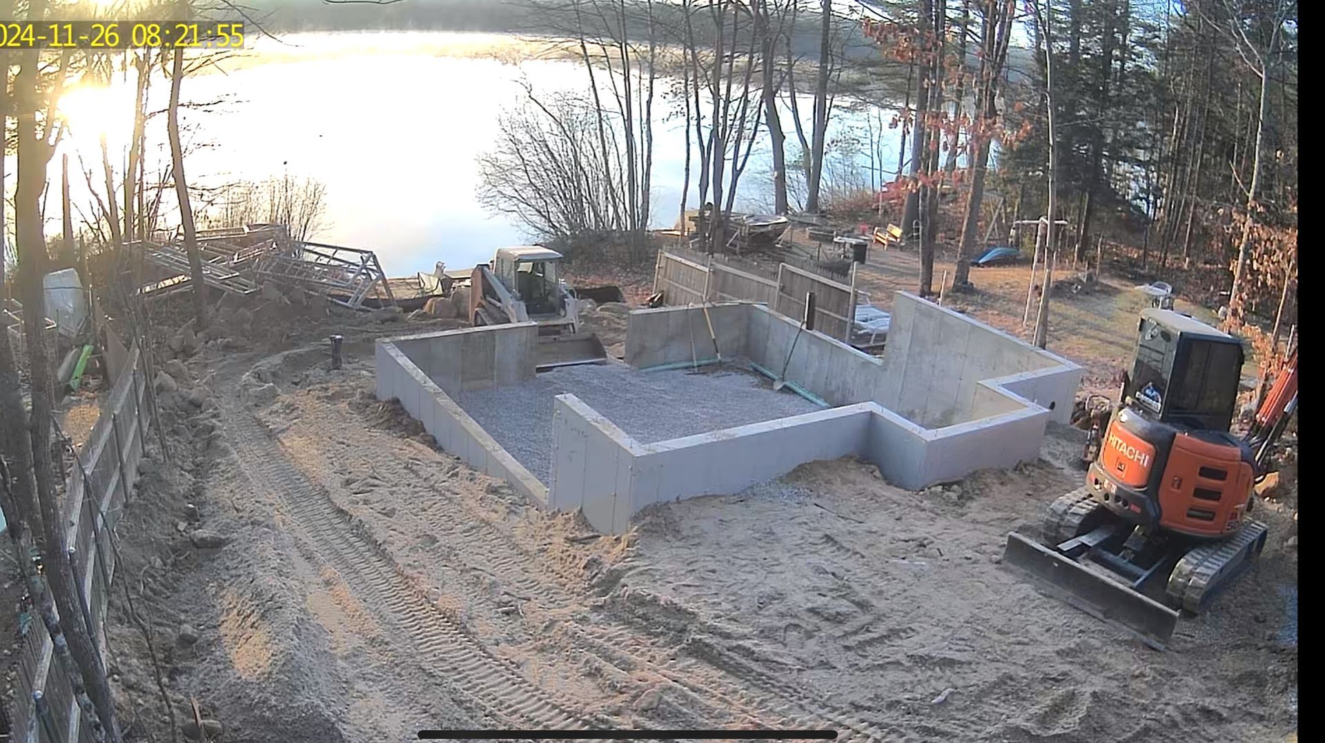 A construction site with a bulldozer in the foreground and a lake in the background