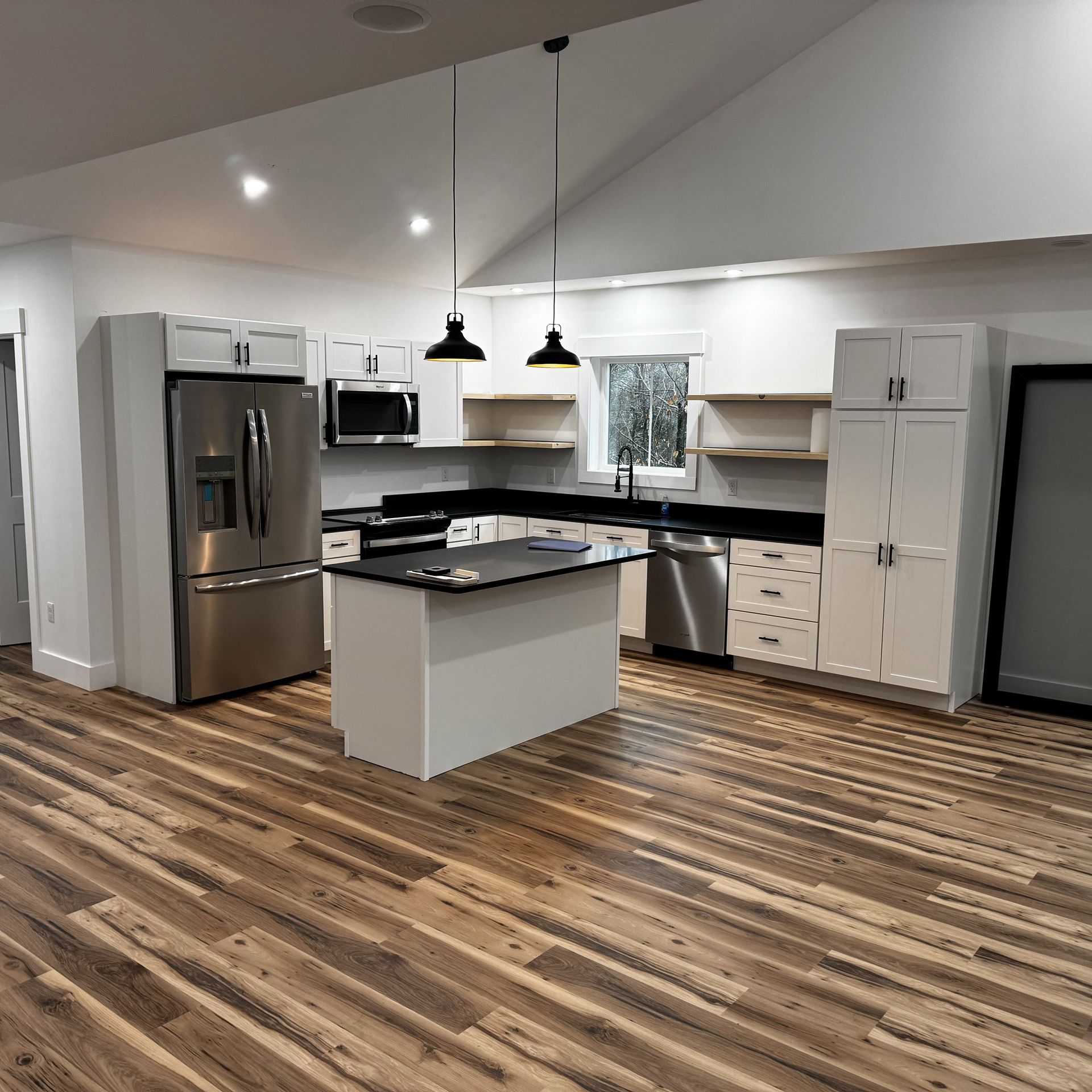 A kitchen with stainless steel appliances and wooden floors.