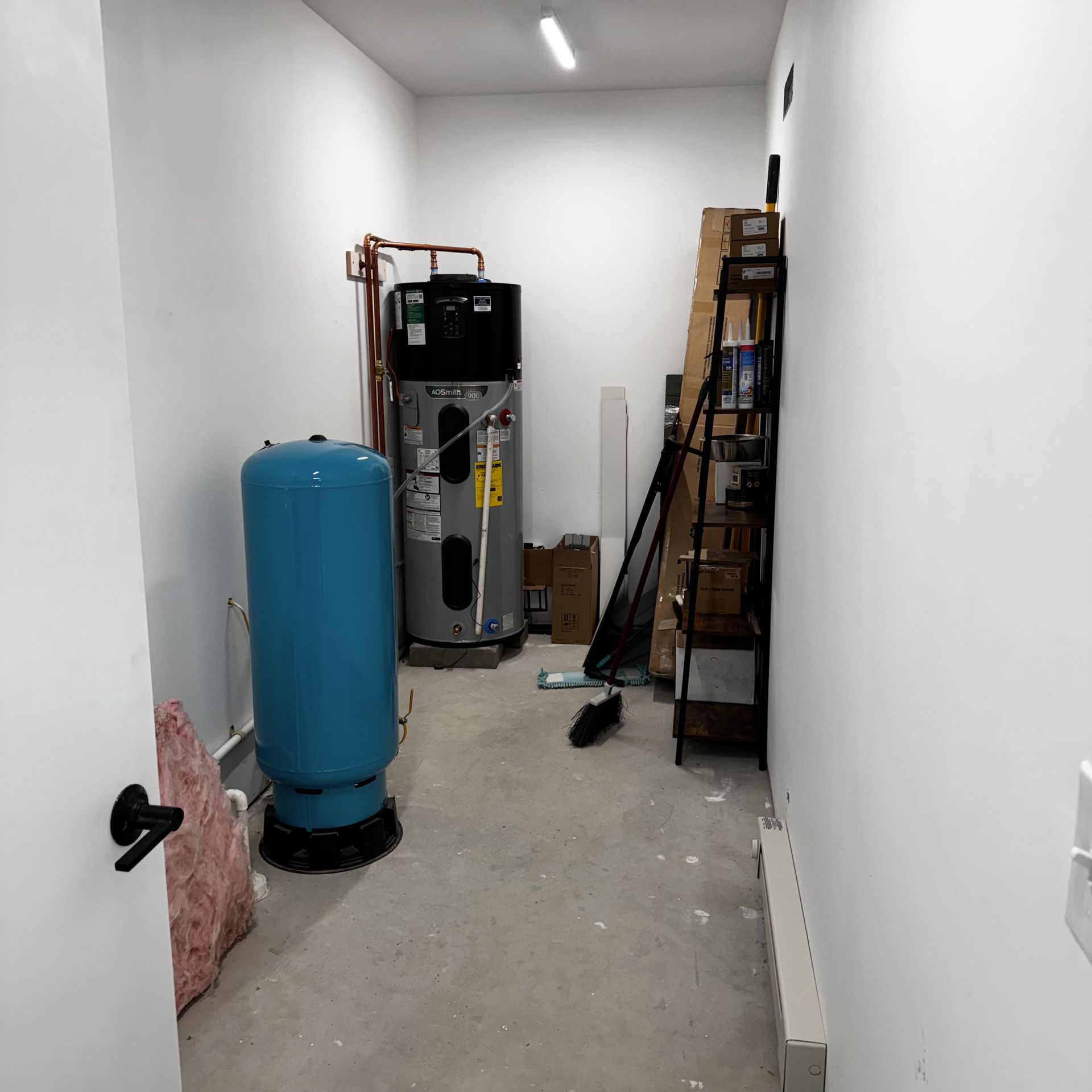 A room with a water heater and a blue tank