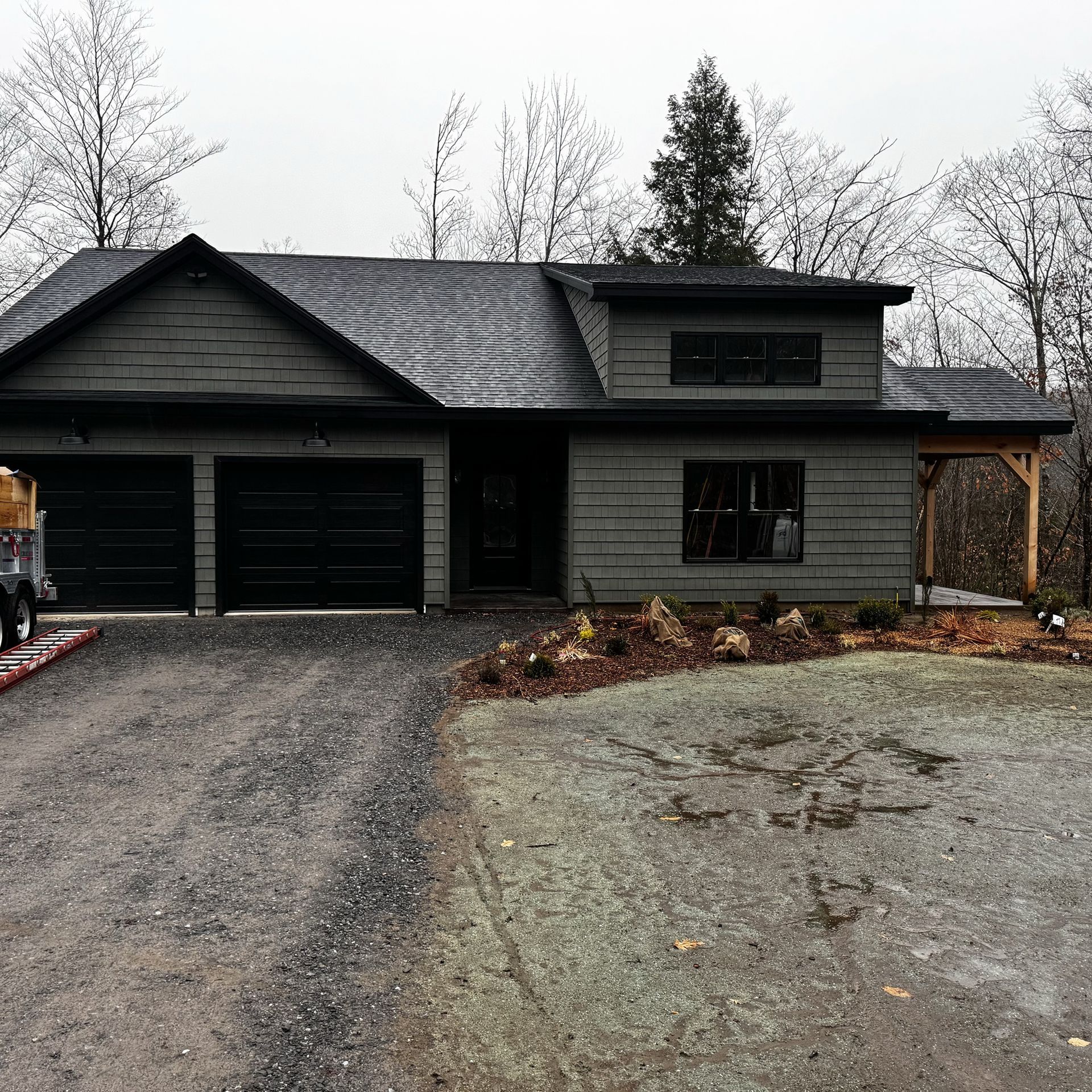 A large house with a slate roof is being built in the woods.