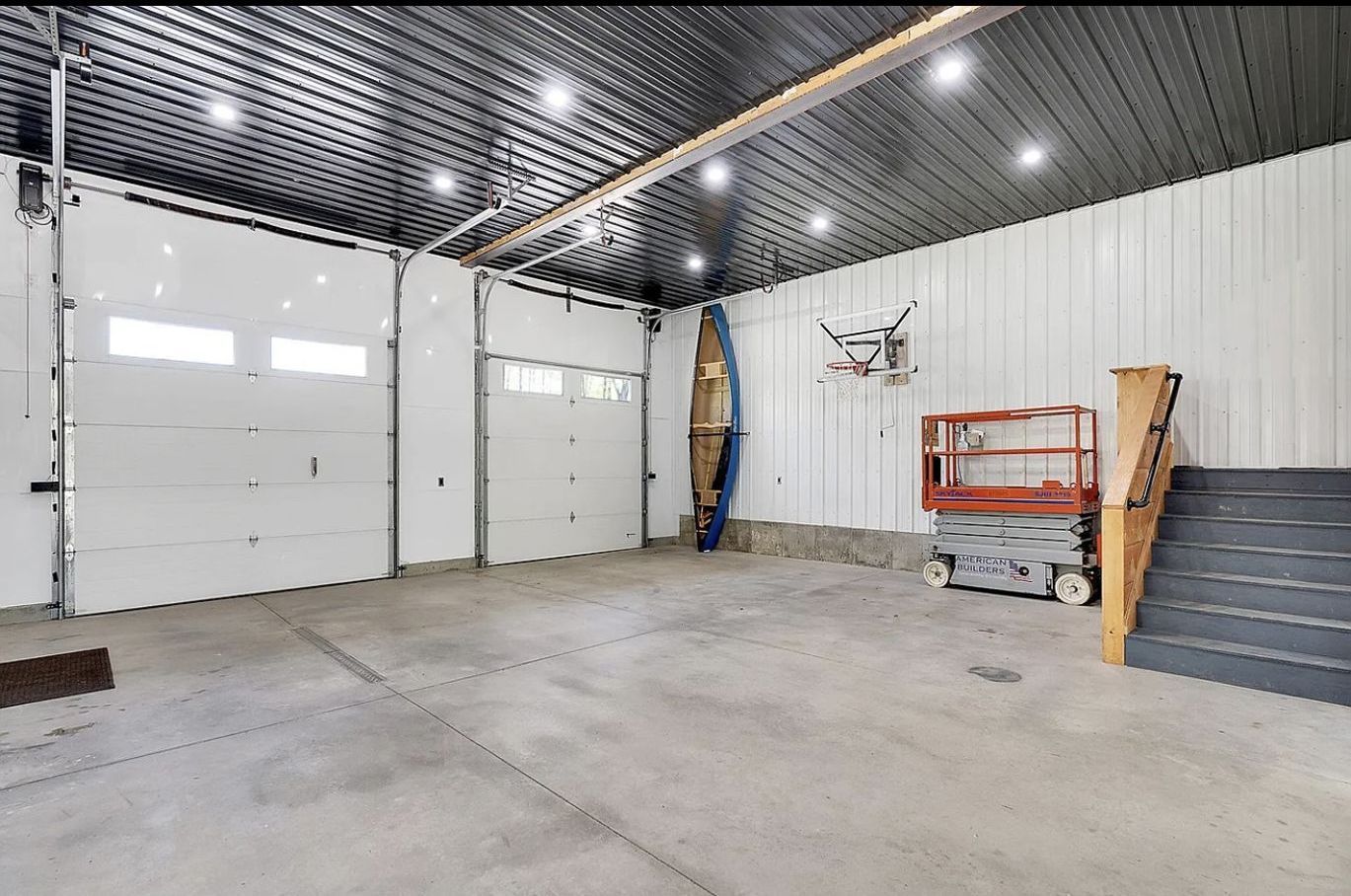 A large empty garage with a staircase and a lift.