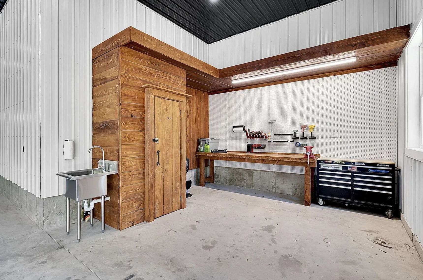 A garage with a sink , workbench , and door.