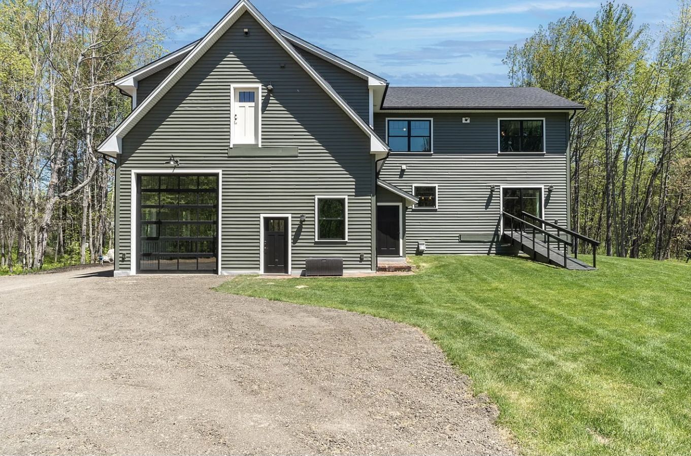 A large gray house with a garage and a ramp in front of it.