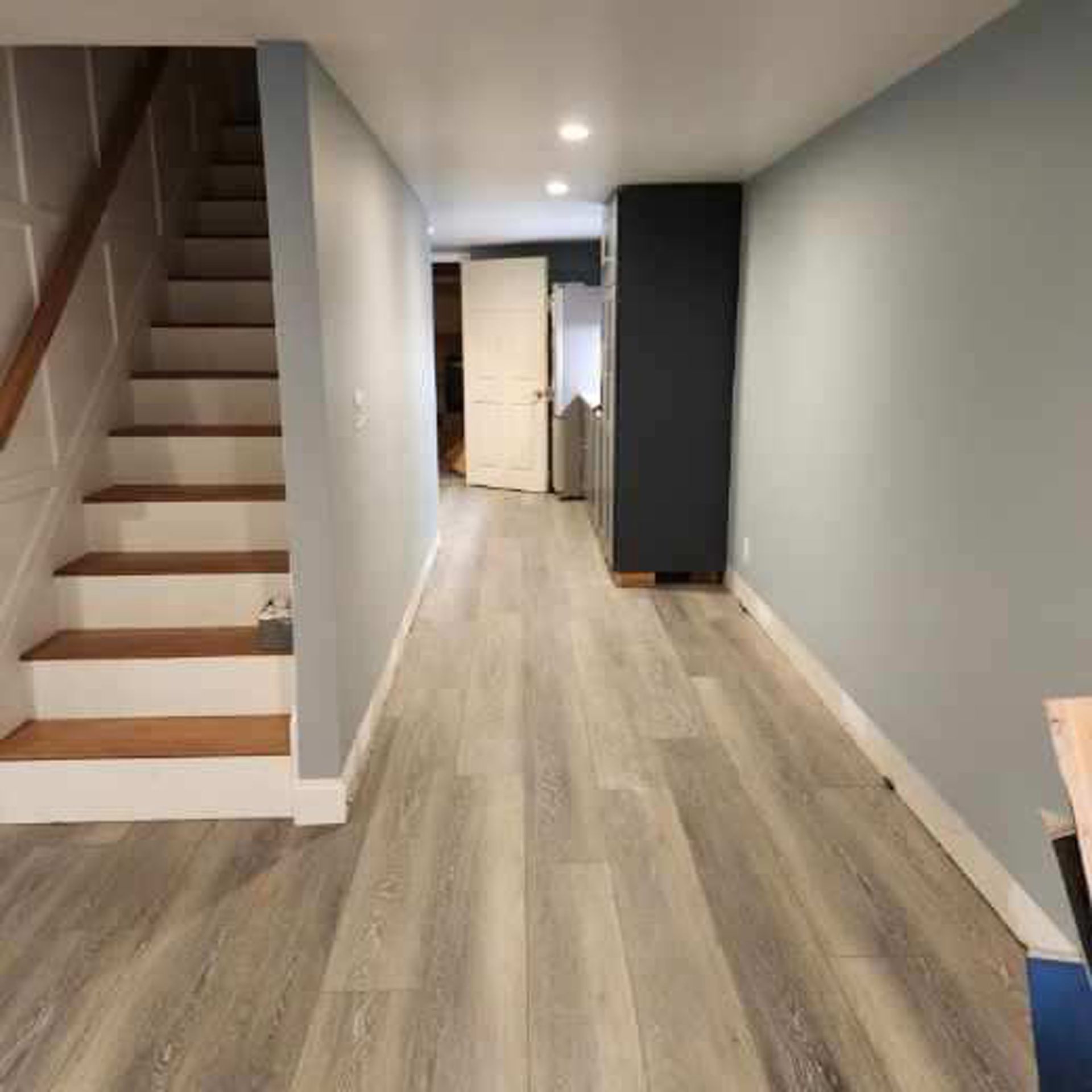 A hallway with hardwood floors and stairs in a house.