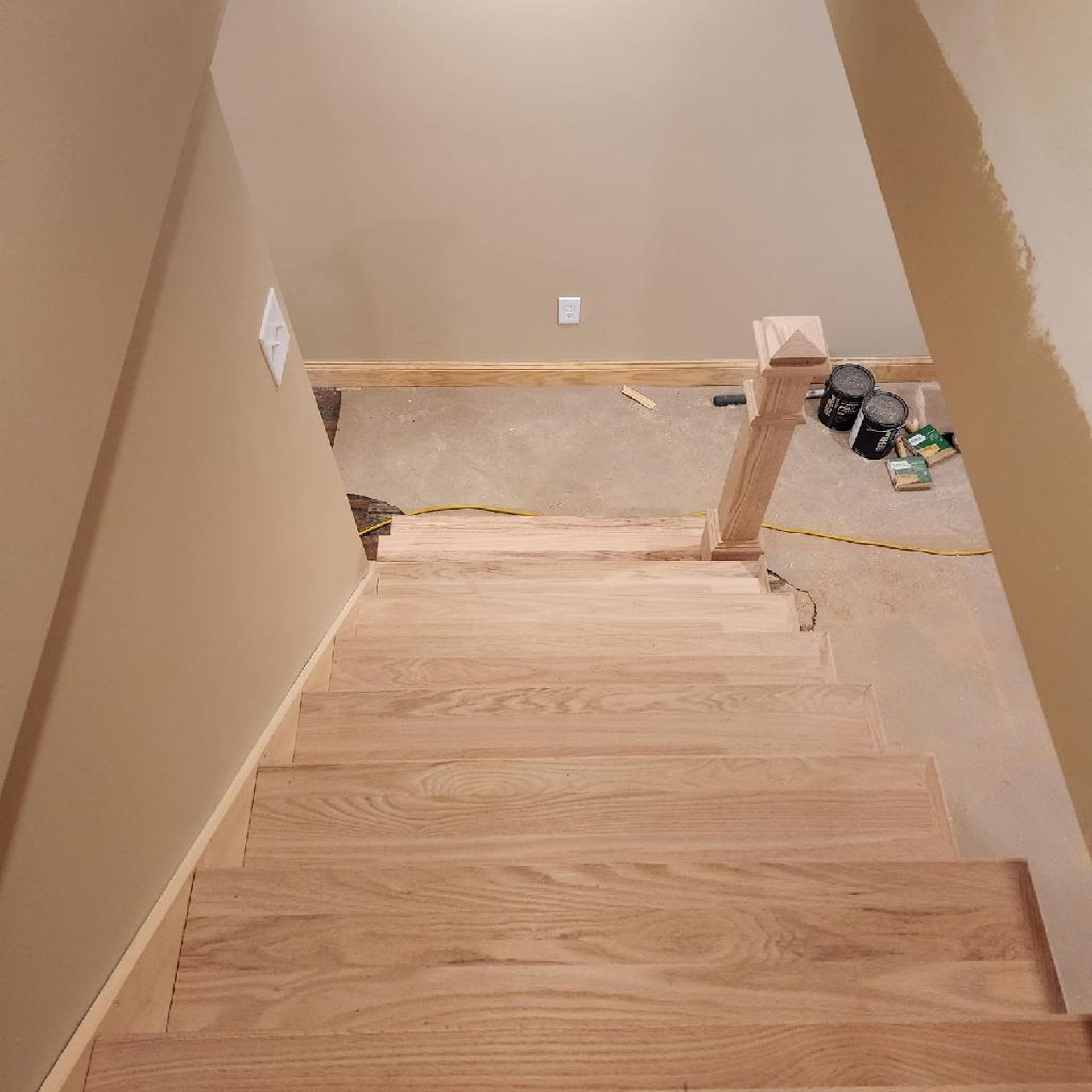 A wooden staircase is being painted in a room.
