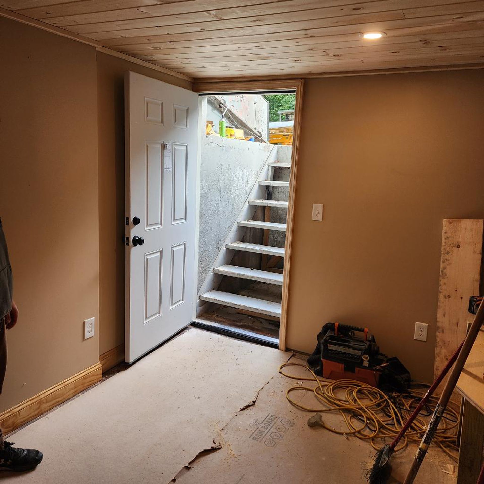 A man is standing in a room with stairs and a door open