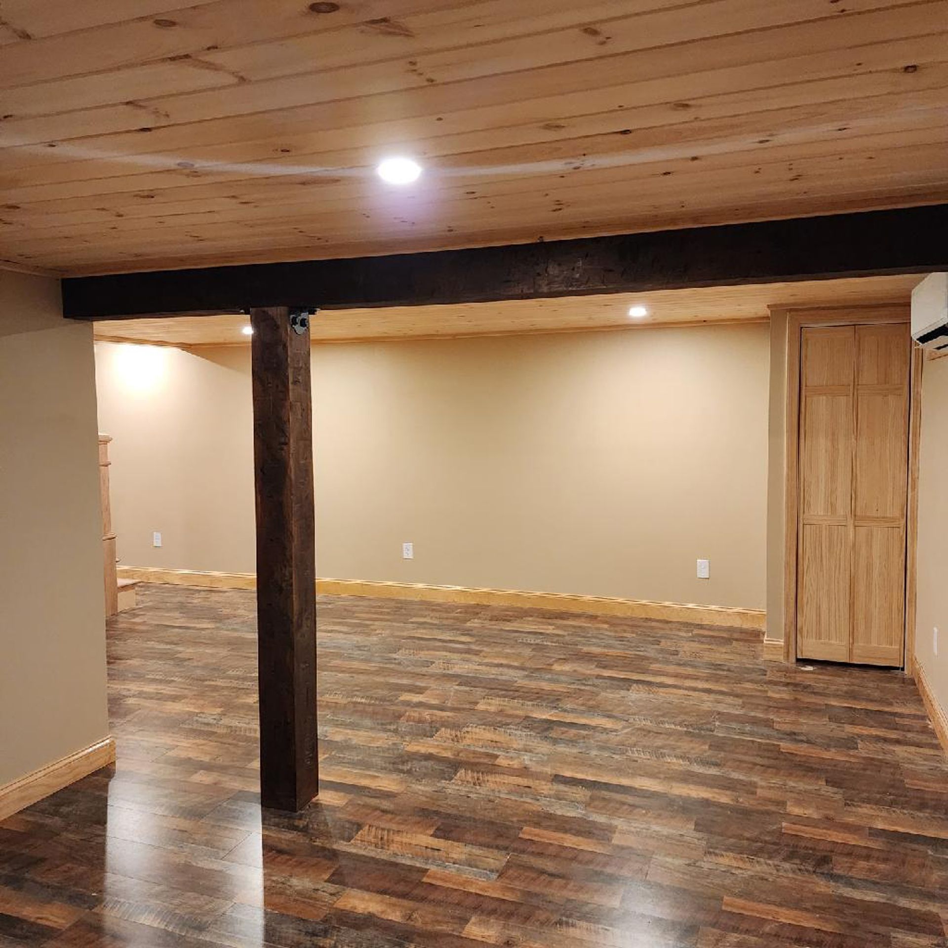 An empty basement with wooden floors and a wooden beam.