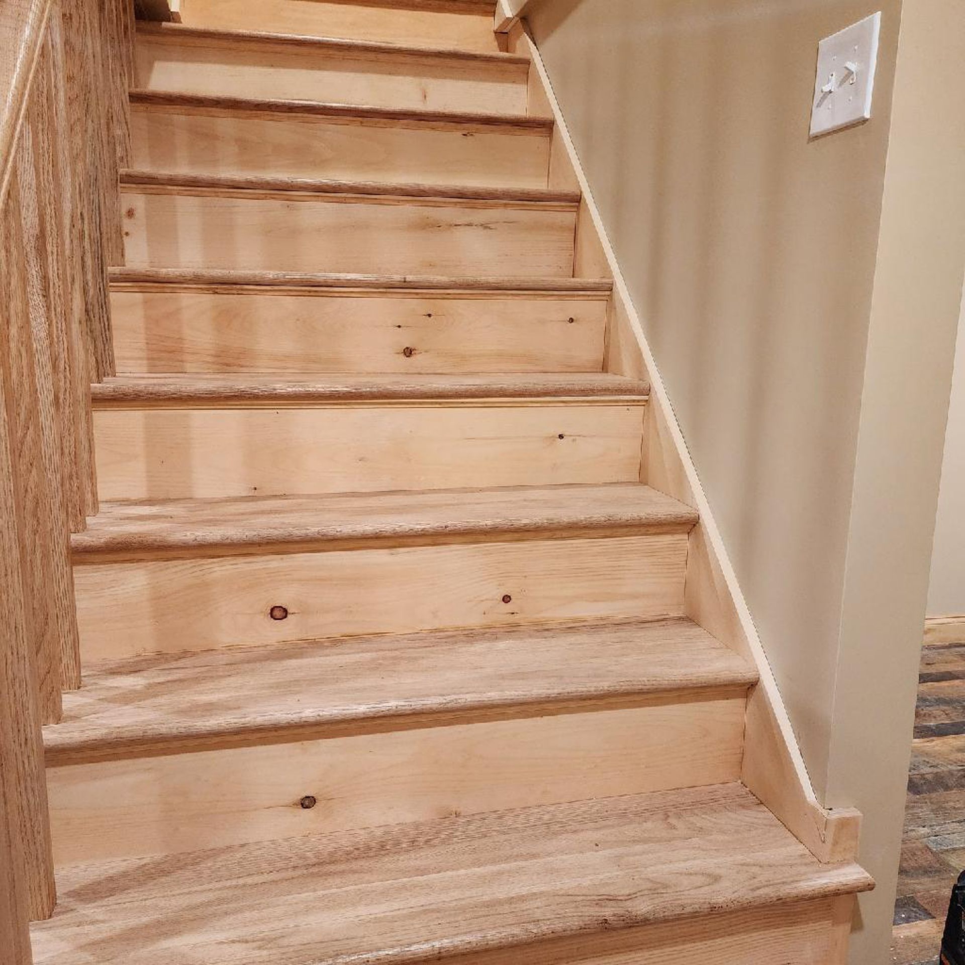 A wooden staircase with a light switch on the wall