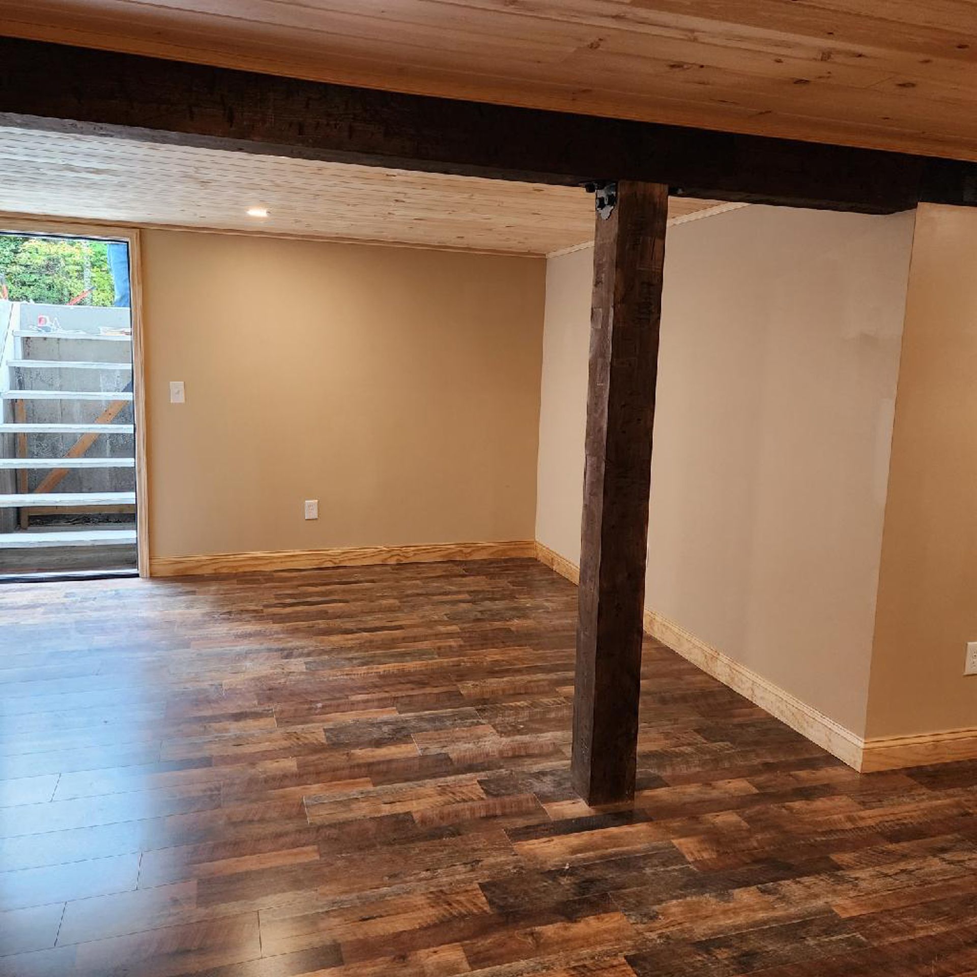 An empty basement with wooden floors and a wooden beam.