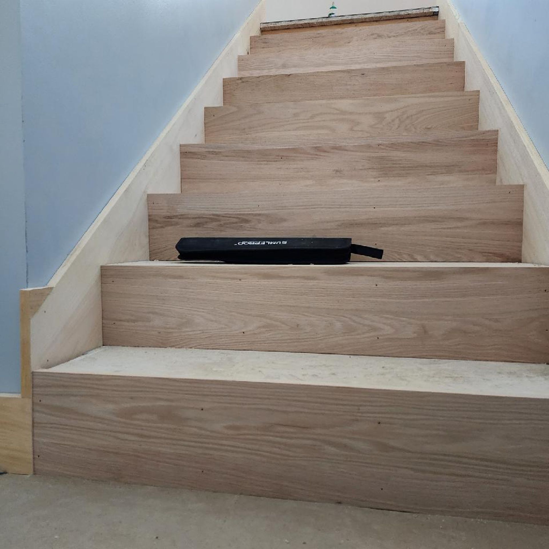 A wooden staircase with a black box on the bottom step