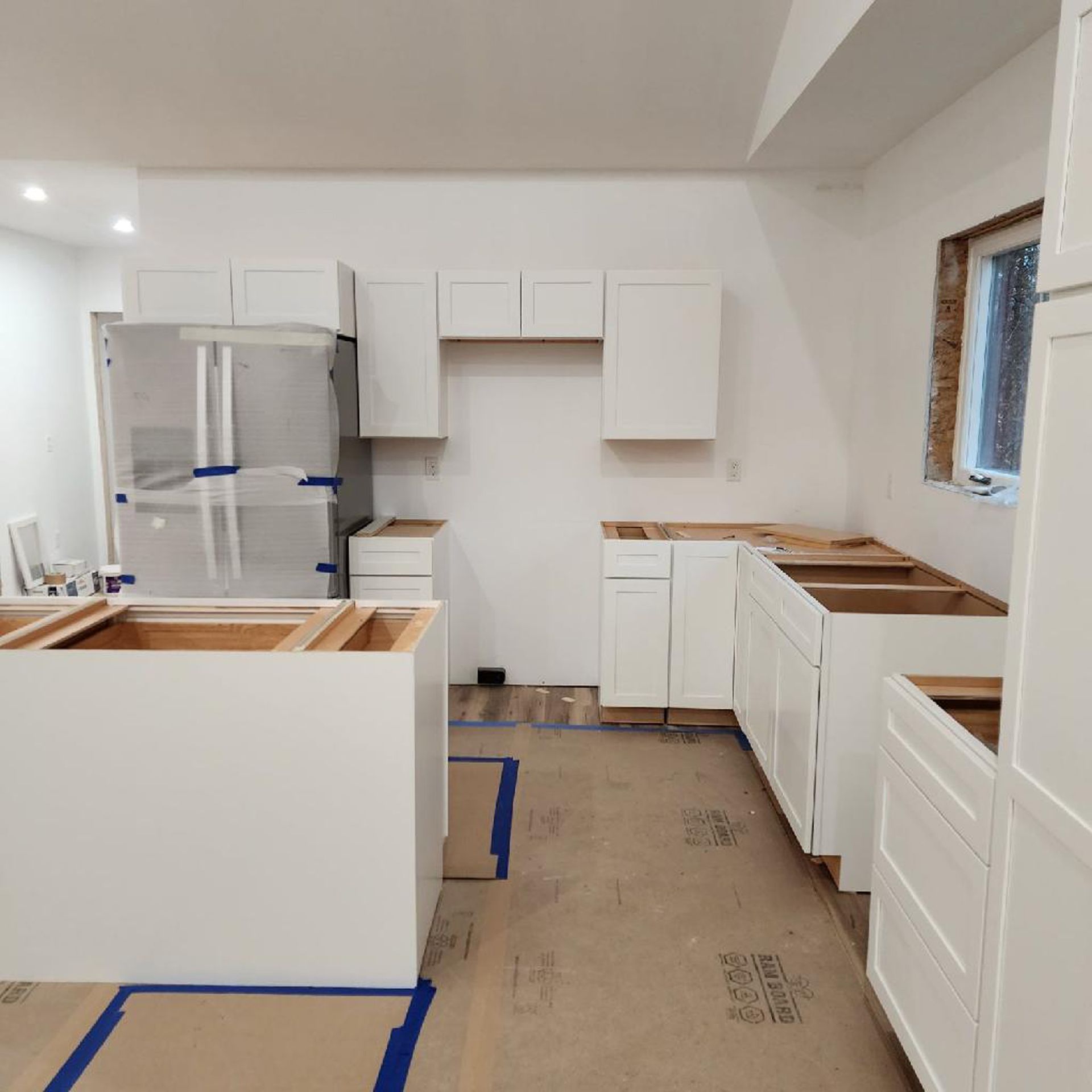 A kitchen under construction with white cabinets and wooden counter tops
