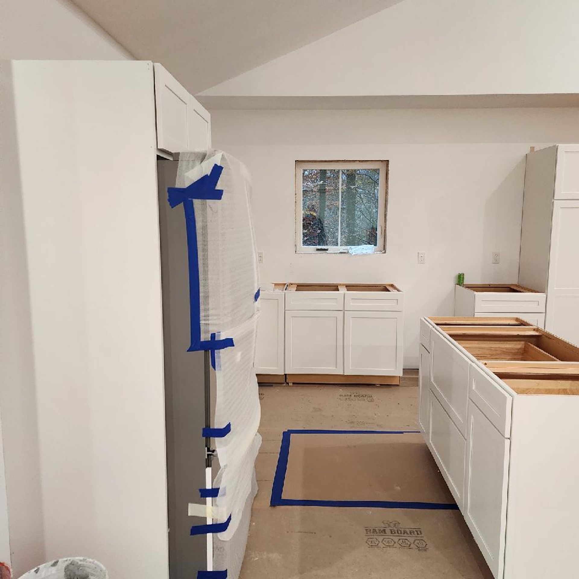 A kitchen with white cabinets and blue tape on the floor