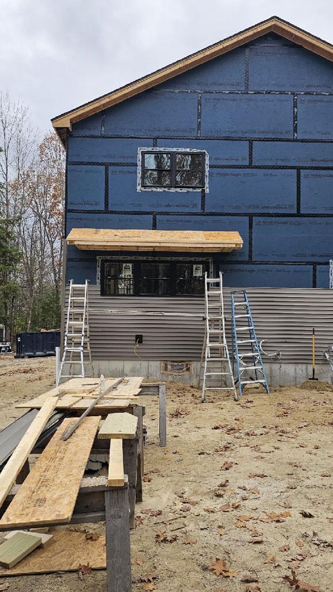 A blue house is being built in the middle of a dirt field.