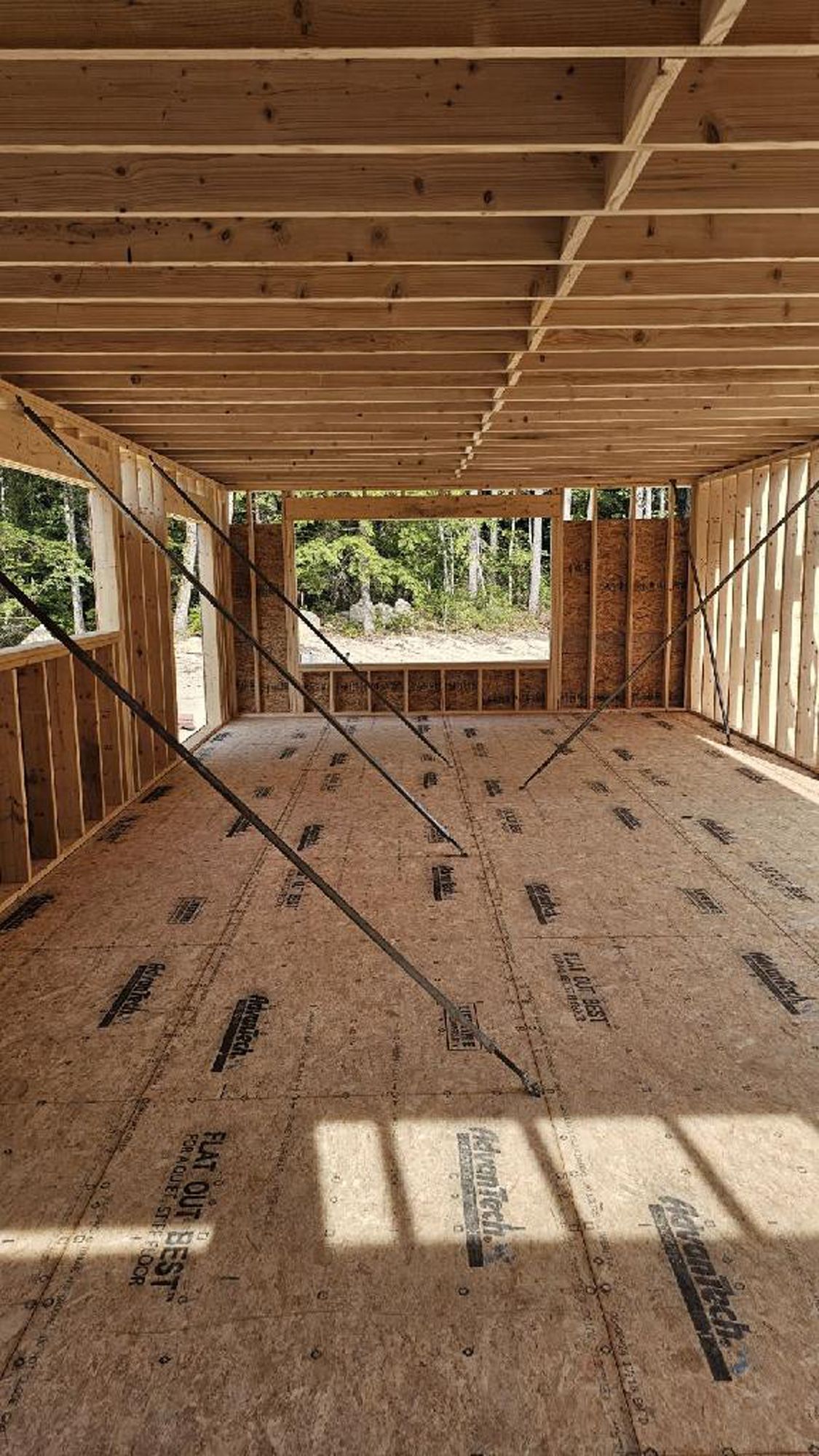 The inside of a house under construction with wooden beams and a wooden floor.