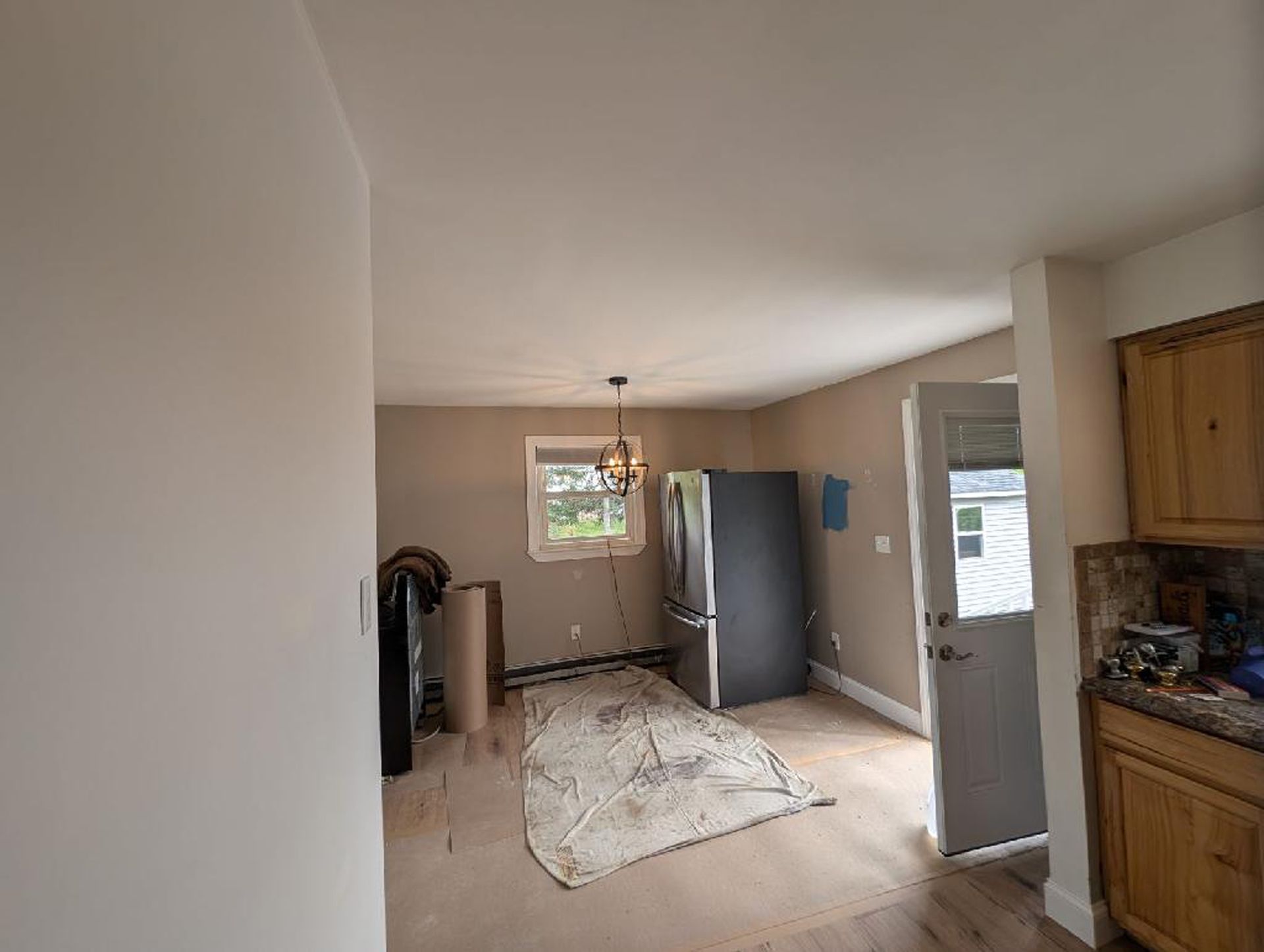 A living room with a refrigerator and a window.