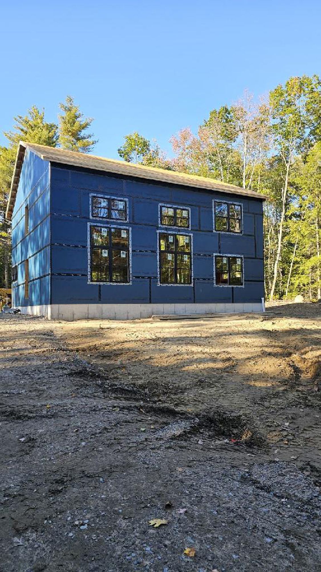 A blue house is being built in the middle of a dirt field.