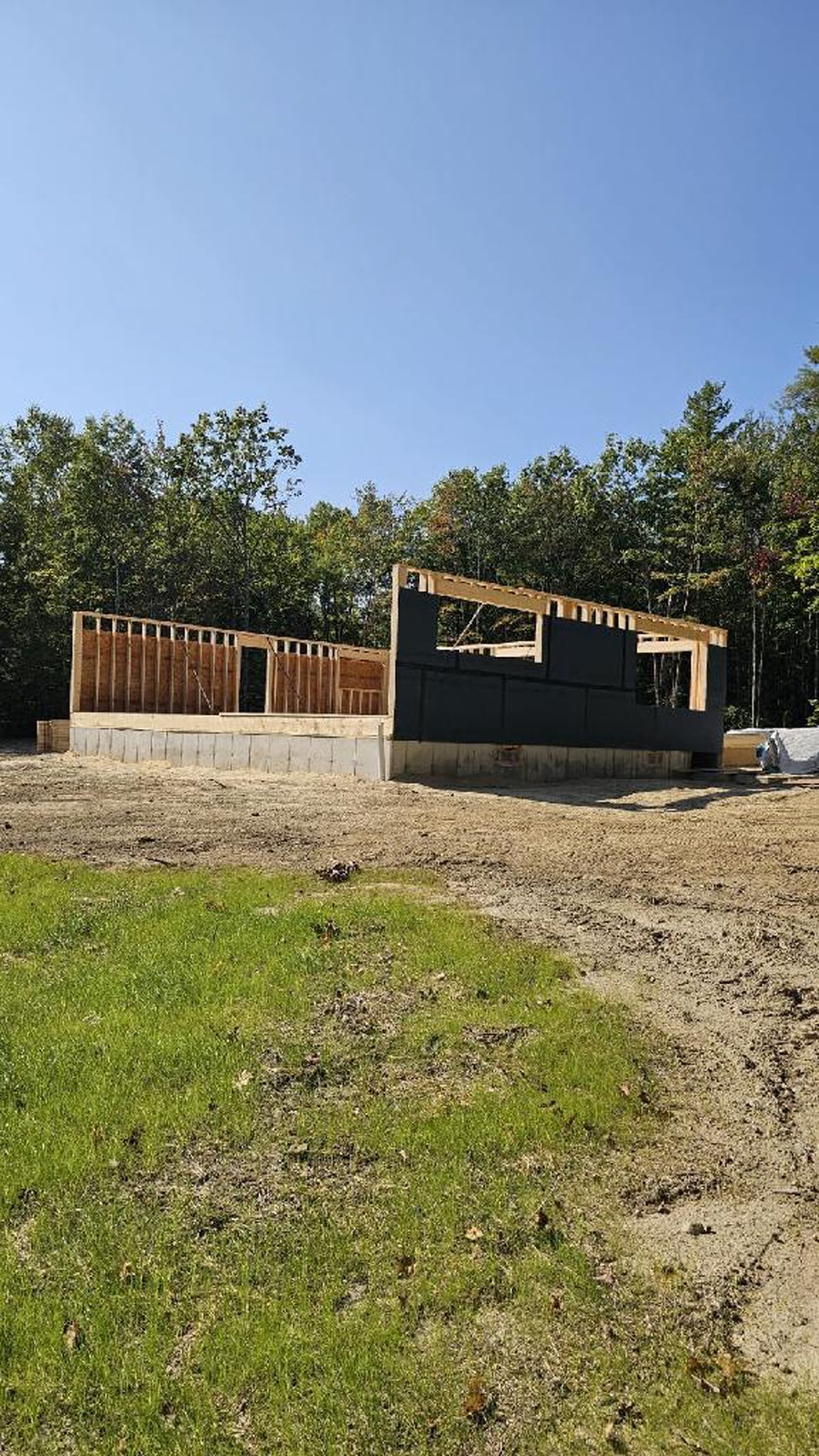 A house is being built in a field with trees in the background.