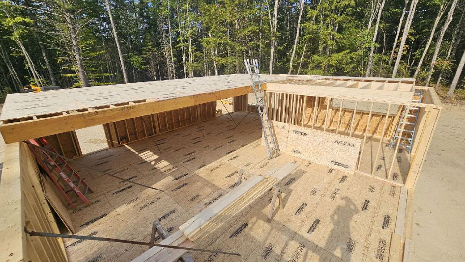 A large wooden structure is being built in the middle of a forest.