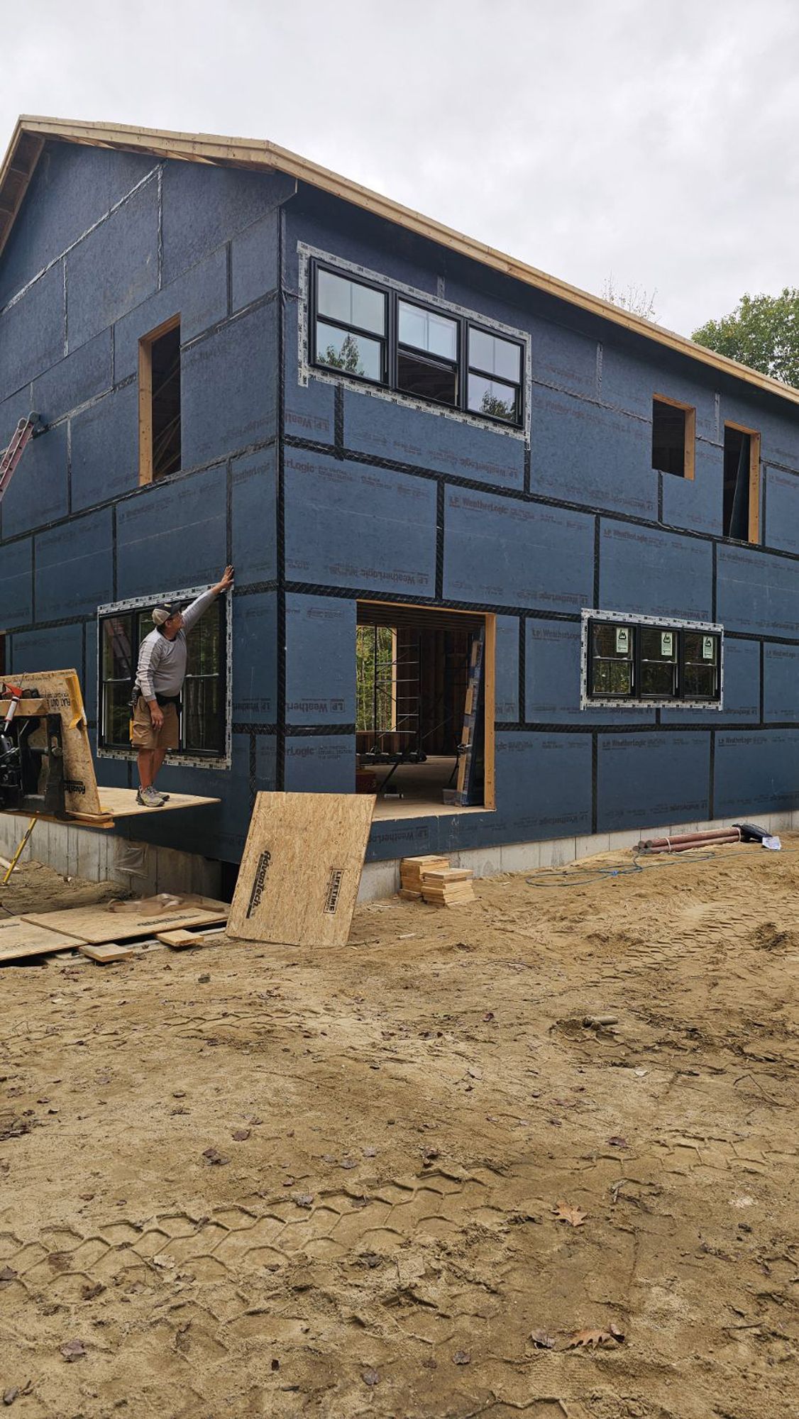 A blue house is being built in a dirt field.