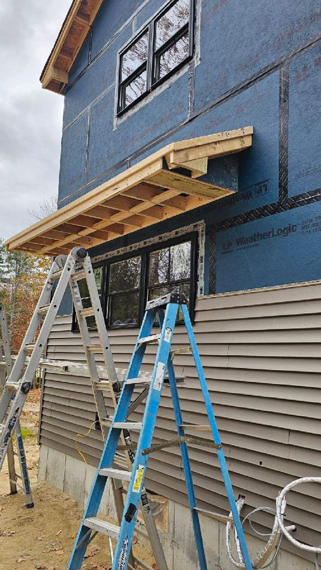 A blue ladder is sitting on top of a blue building.