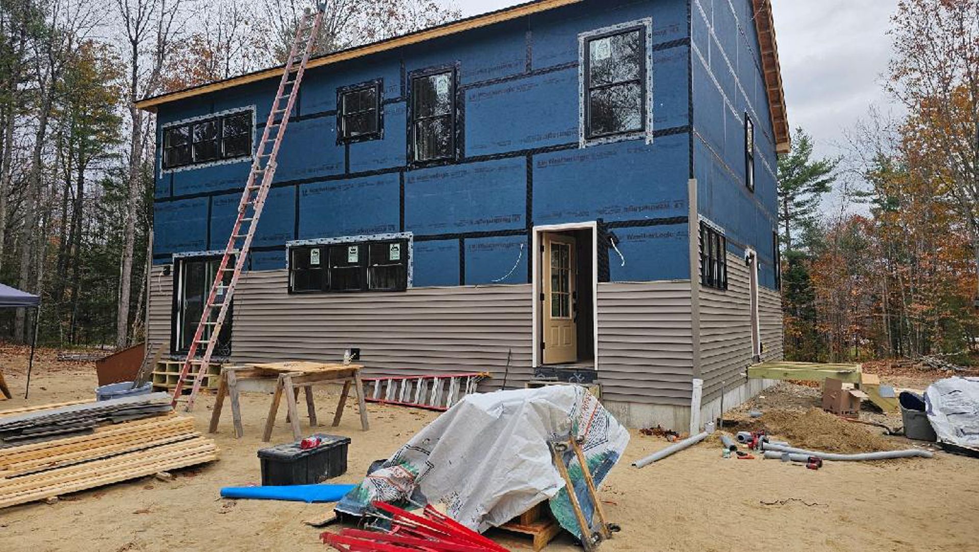 A large blue house is being built in the middle of a forest.