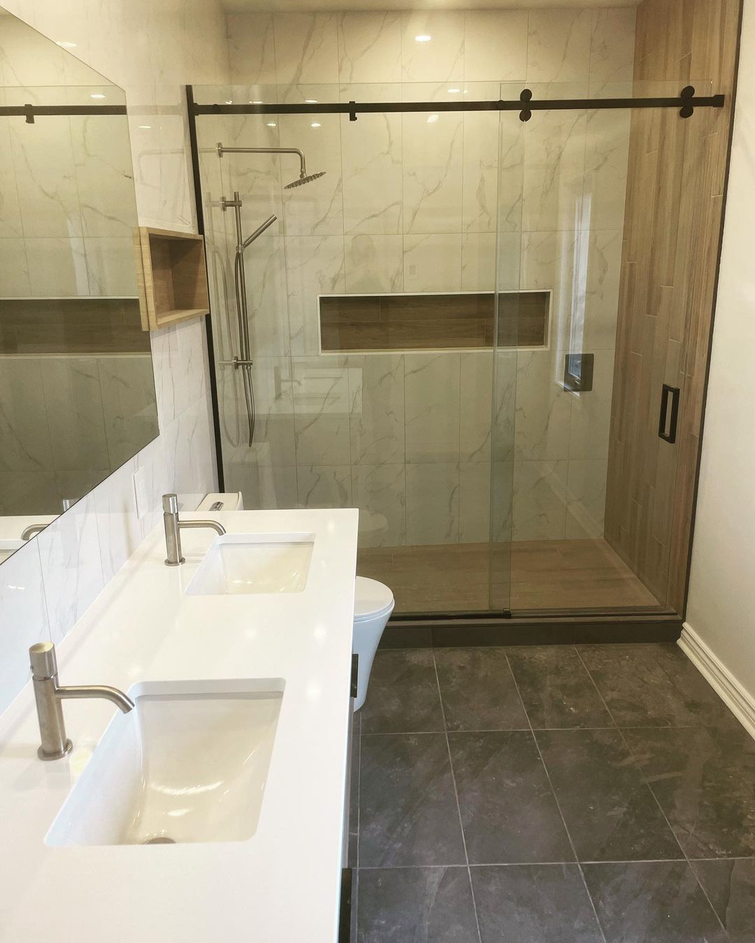 Une salle de bain avec lavabo, WC, douche et miroir.