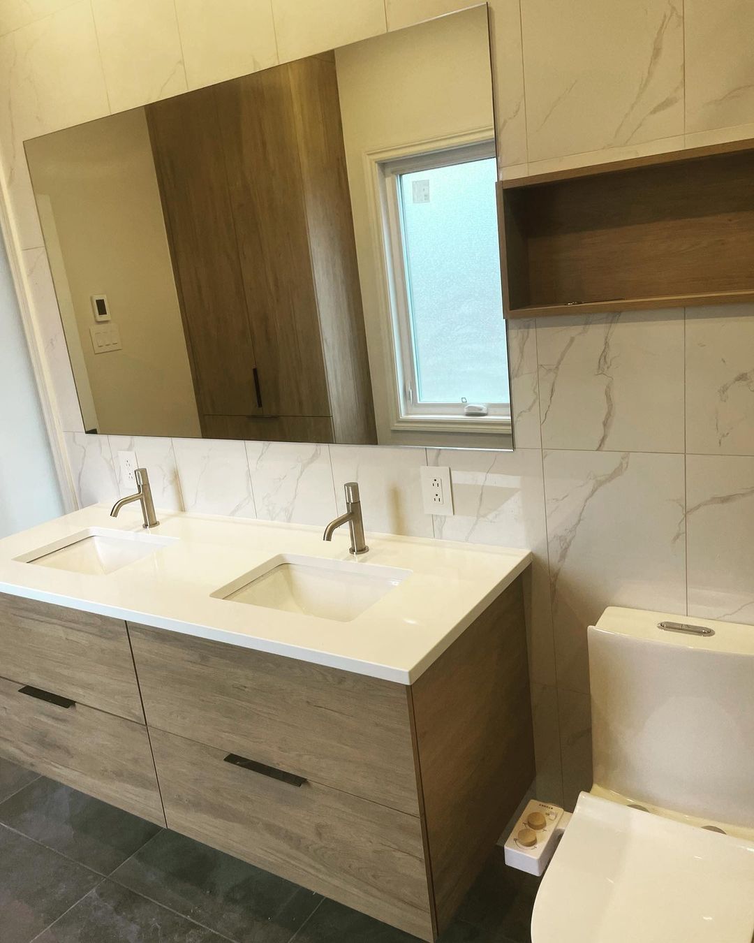 Une salle de bain avec deux lavabos, un WC et un grand miroir.