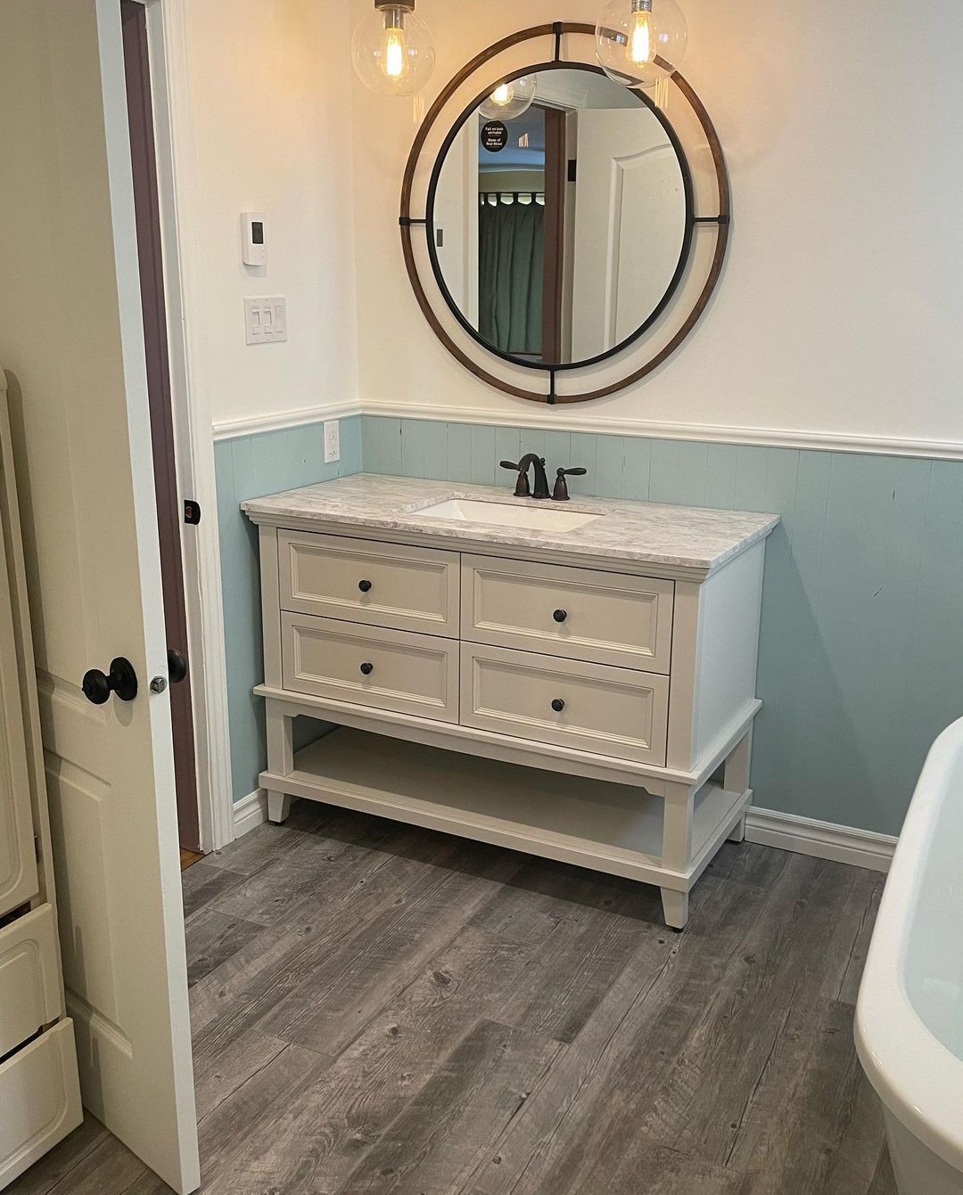 Une salle de bain avec lavabo, miroir et baignoire.