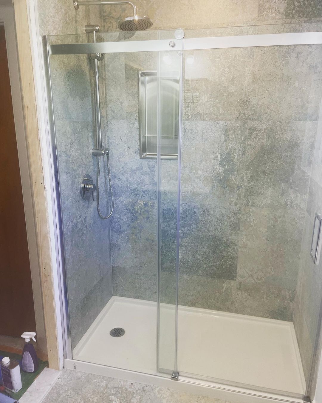 Une salle de bain avec une porte de douche coulissante en verre et une pomme de douche.