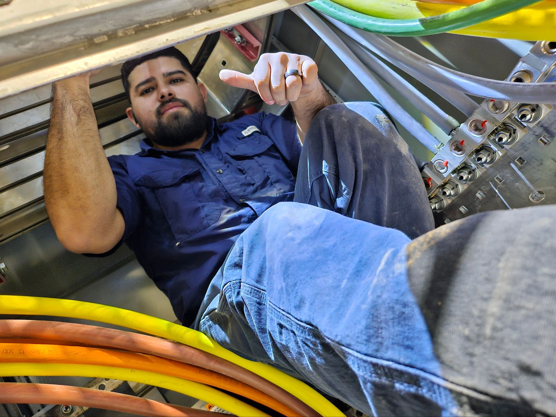 A man with a beard is laying on the ground in a room with a bunch of wires.