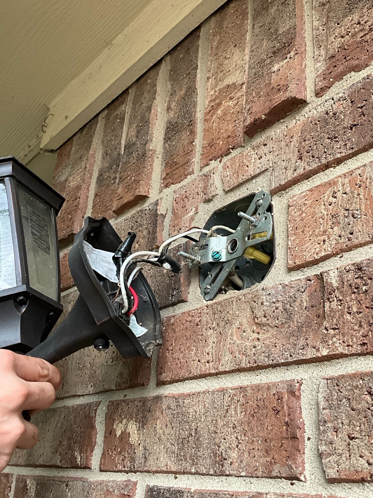 A person is installing a light on a brick wall.