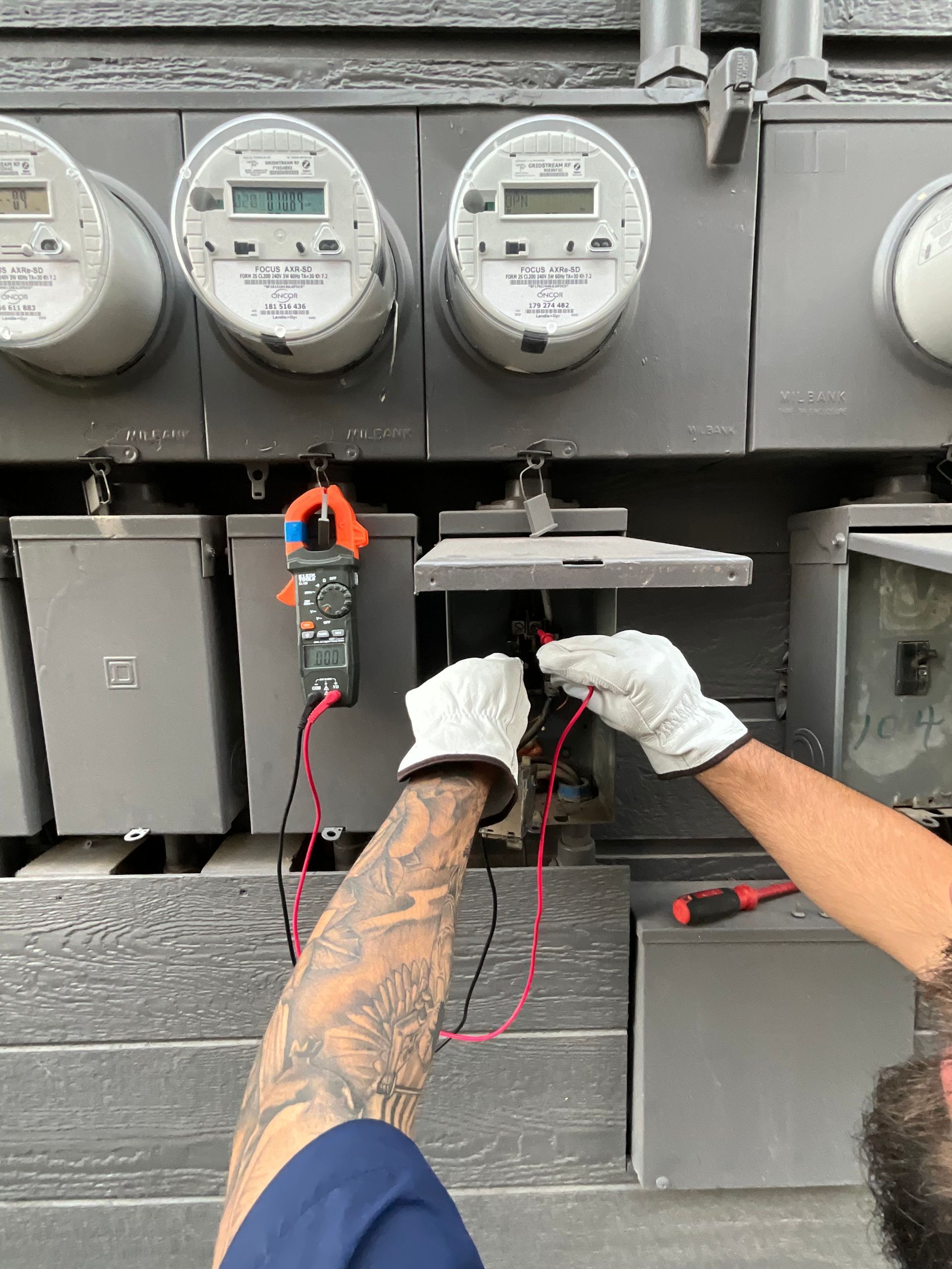 A man is working on an electric meter with a clamp.