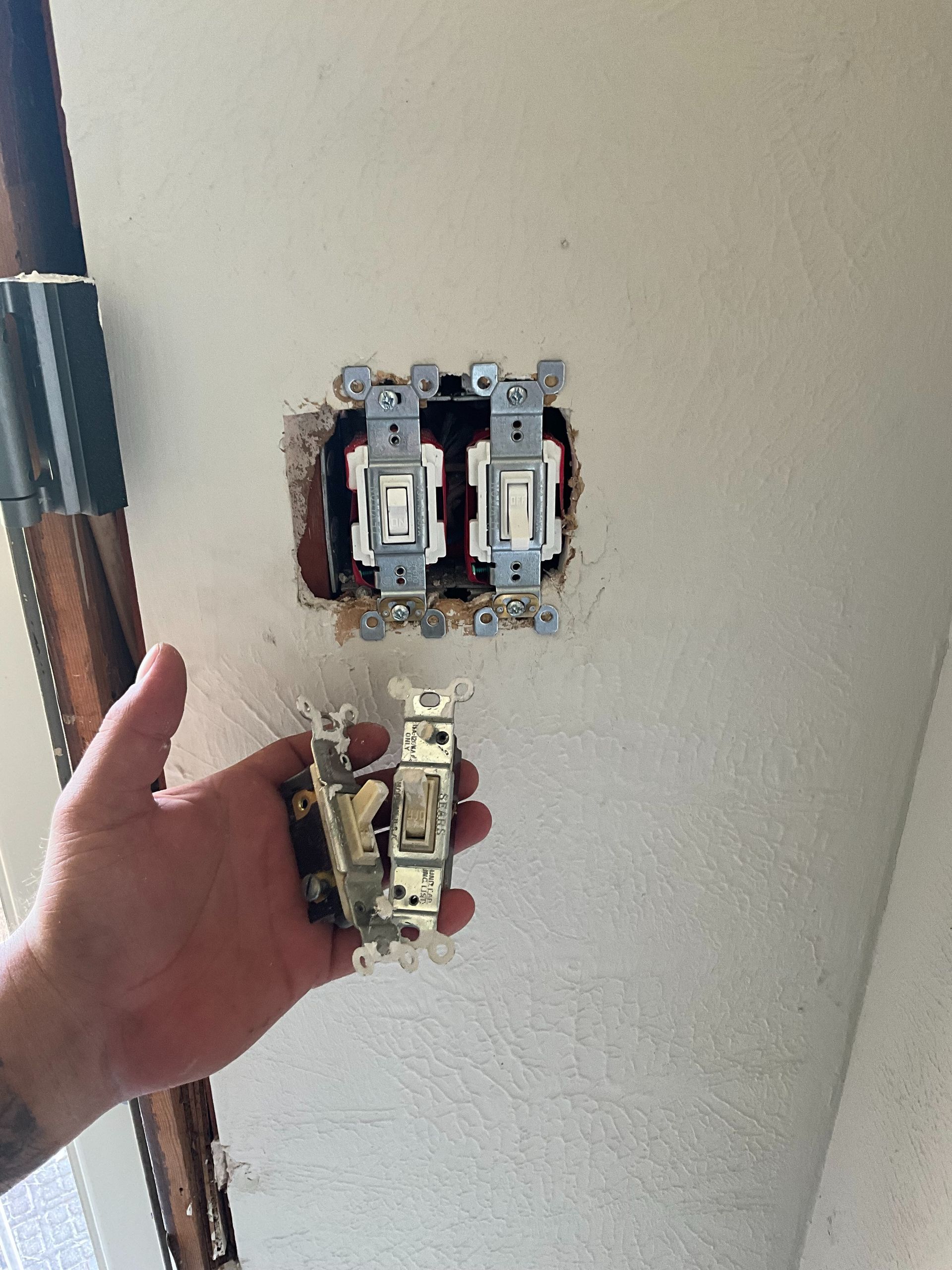 A person is holding a light switch in their hand.