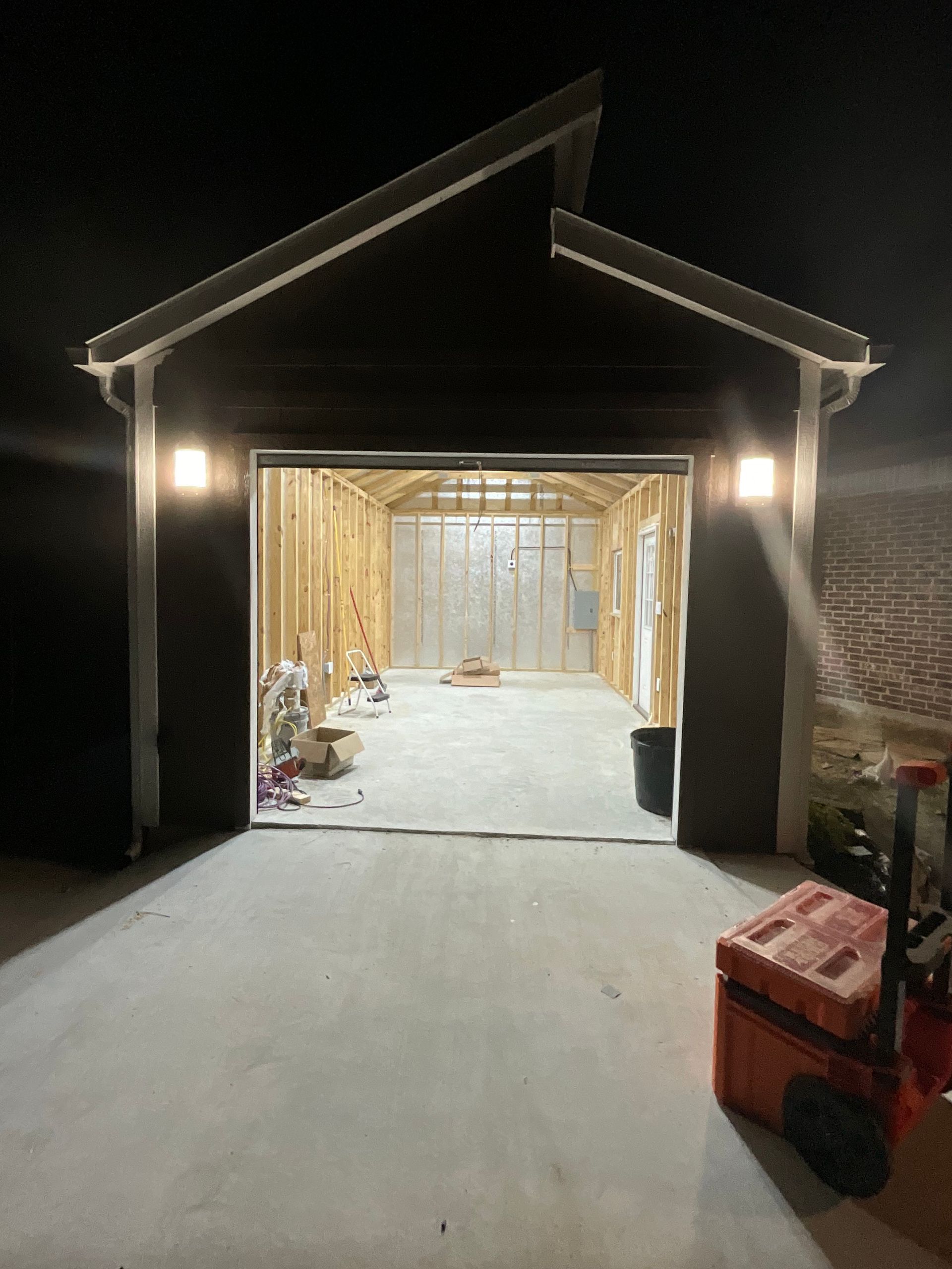 A garage is being built at night and the door is open.