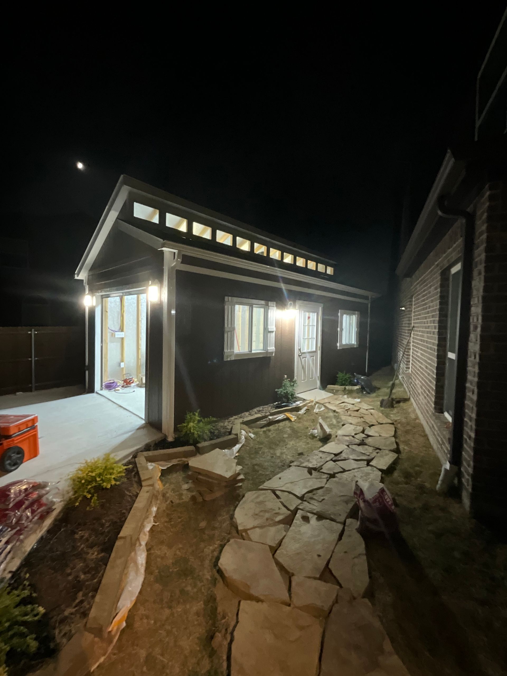 A house with a stone walkway leading to it is lit up at night.