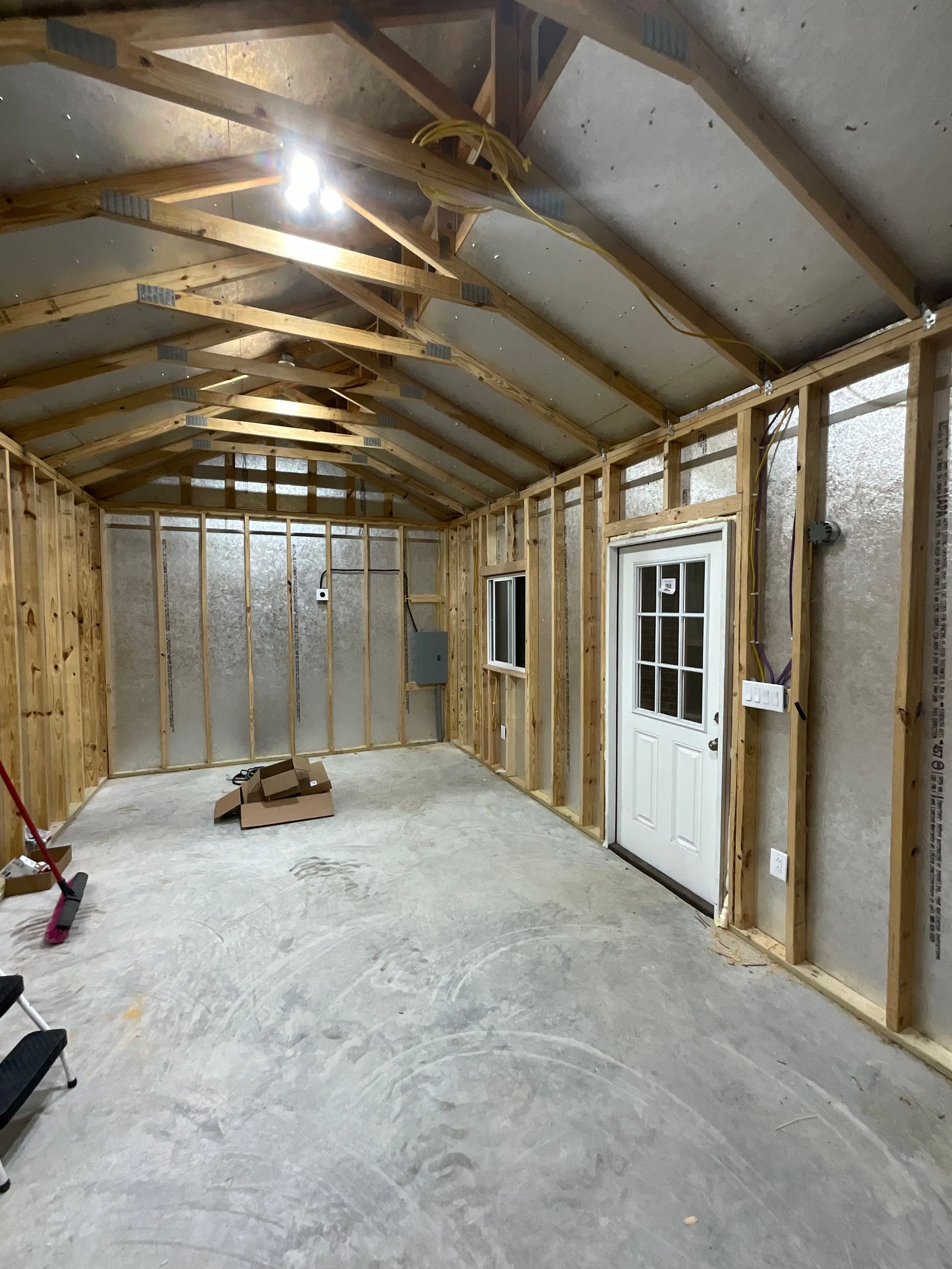A large empty room with wooden beams and a white door.