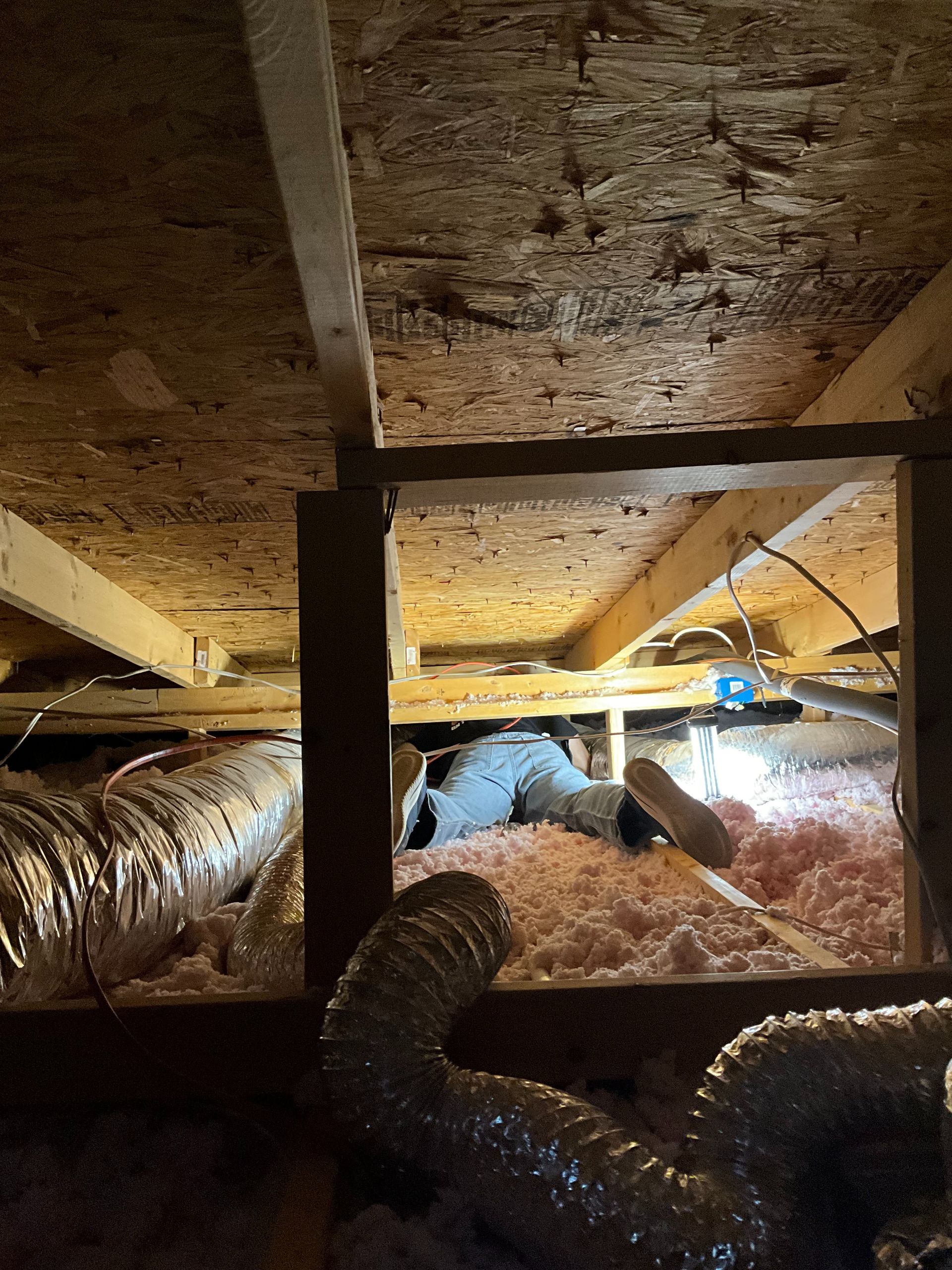 An attic with a lot of ducts and insulation