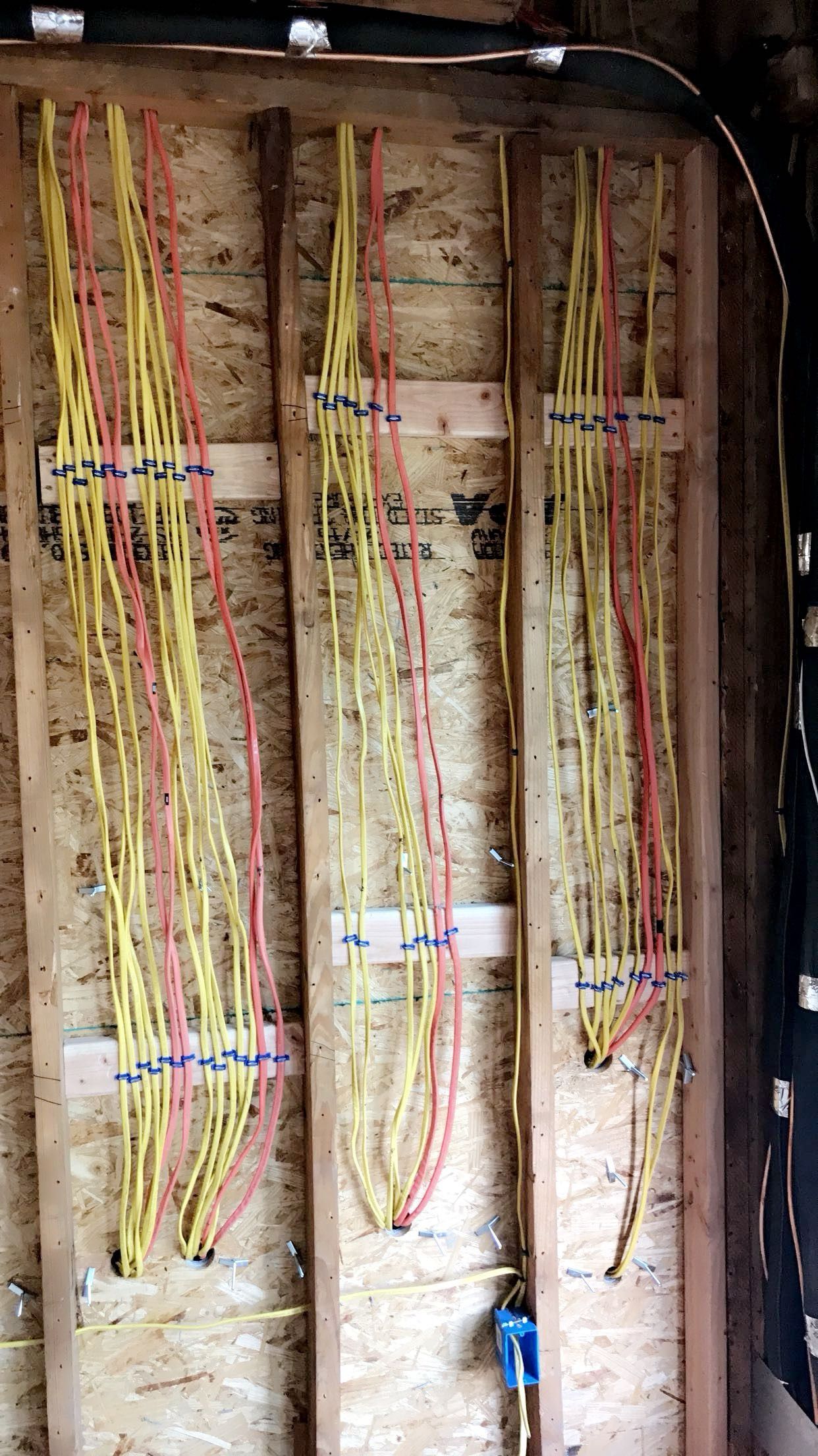 A bunch of wires are hanging on a wooden wall.