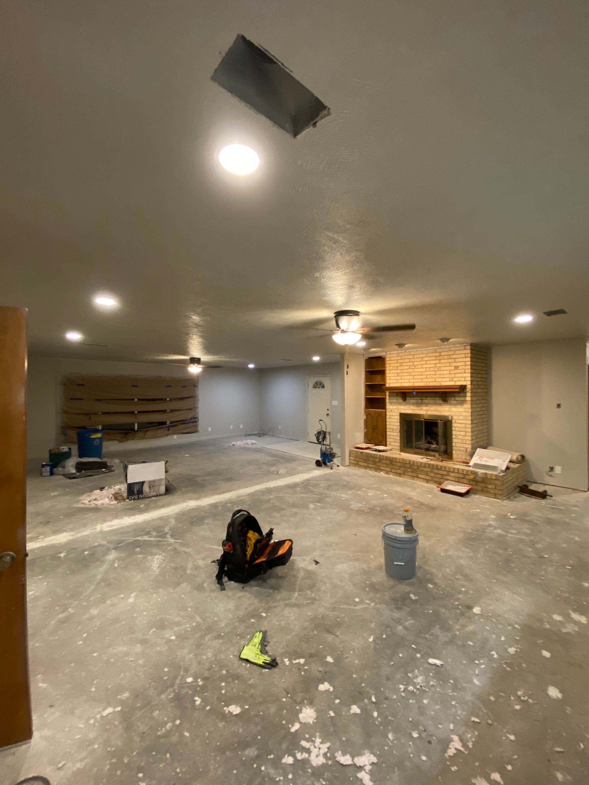 A large empty room with a fireplace and a ceiling fan.