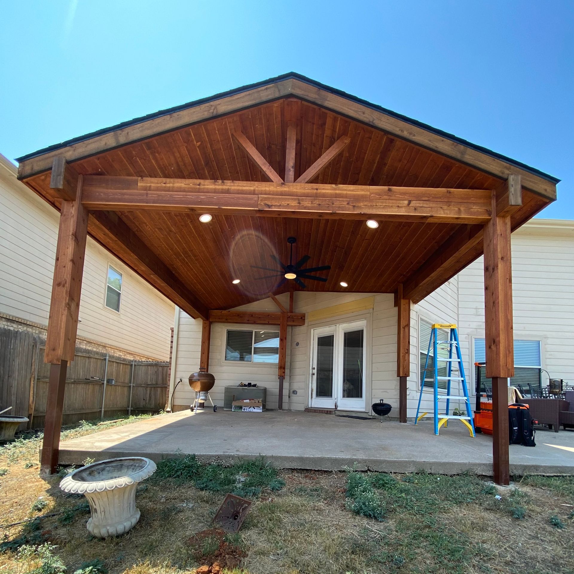 A house with a covered patio and a ladder in front of it