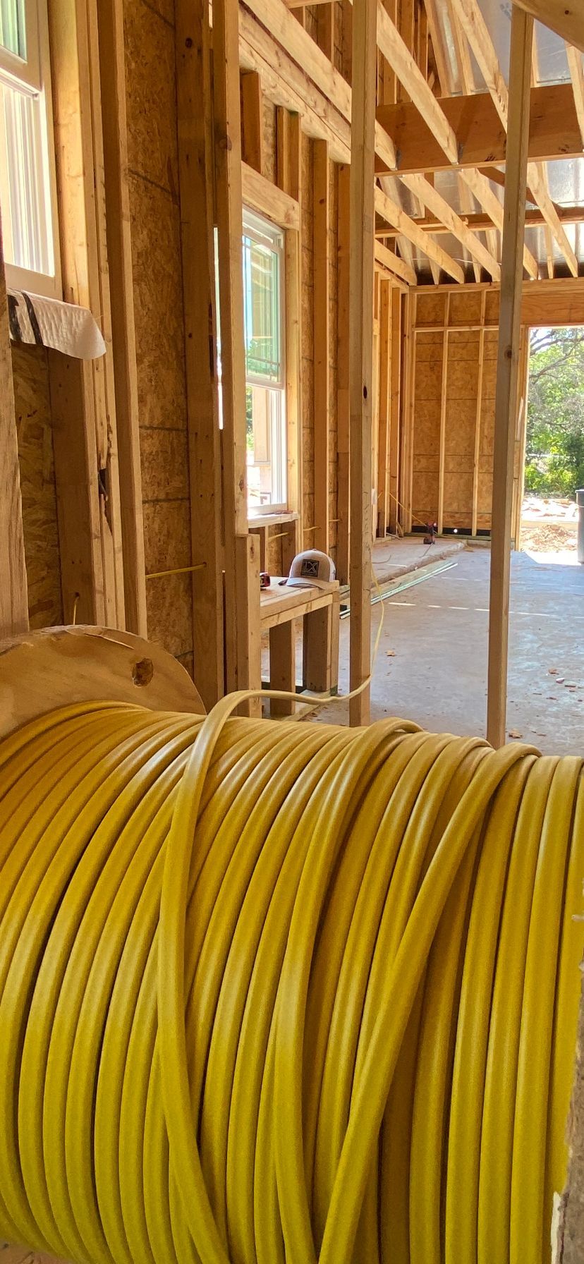 A roll of yellow hose is sitting inside of a house under construction.
