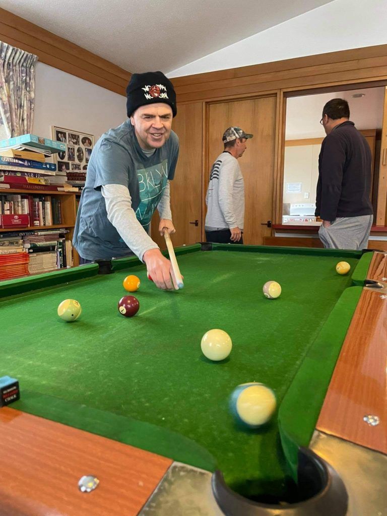 A man is playing pool in a room with other men.