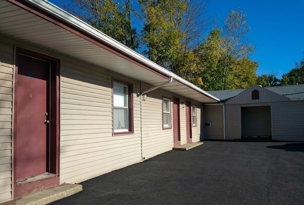 A long, light-colored brick building with red doors and an adjacent garage under a bright blue sky.